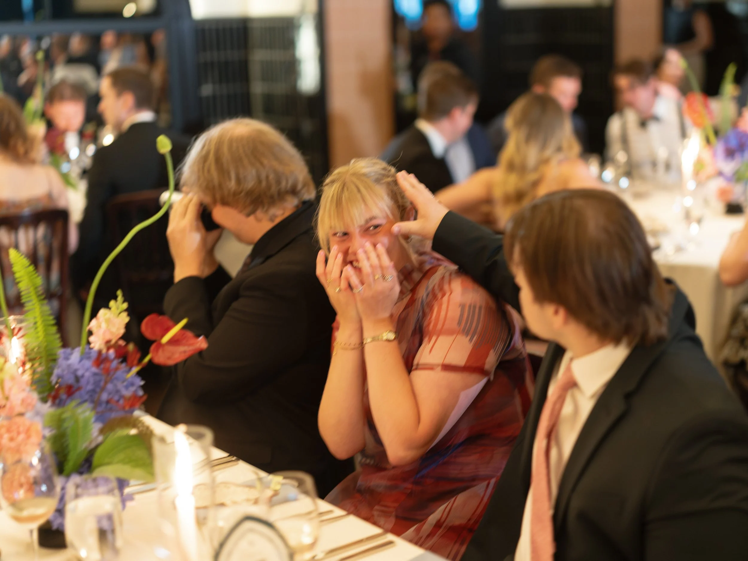 A guest reacts with laughter and emotion at the reception table