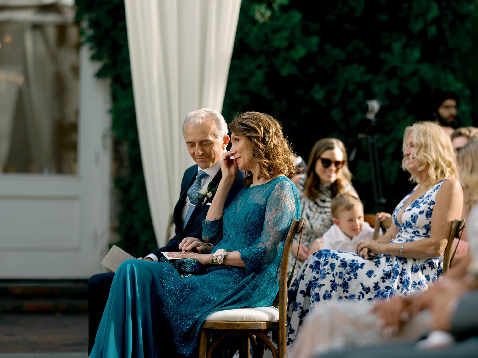 A visibly moved guest dabs tears from her eyes during the ceremony at the Chicago Illuminating Company, overcome with emotion in the sunlit garden.