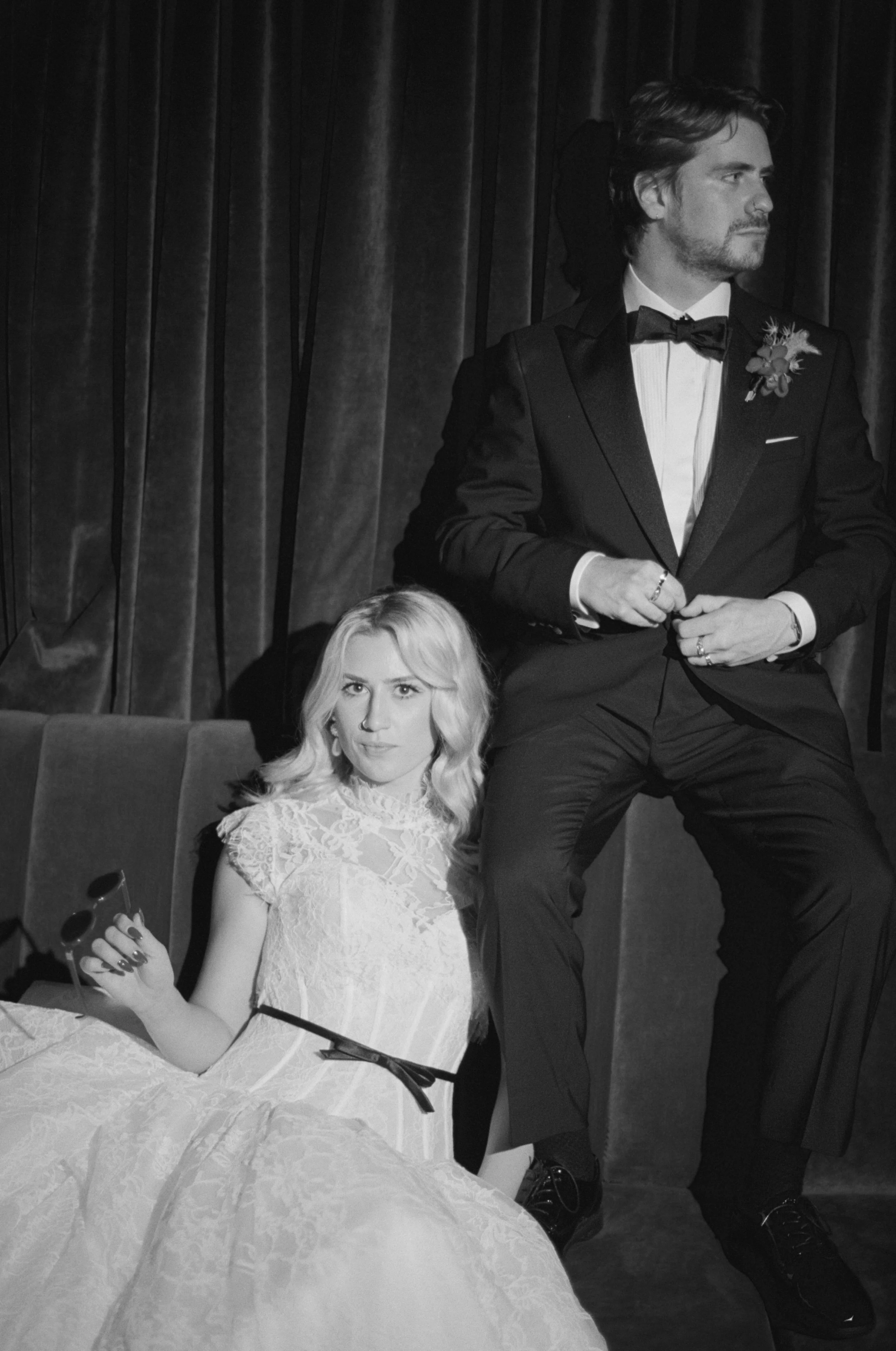 Black and white portrait of the bride and groom seated together in The Wellsley's red velvet lounge