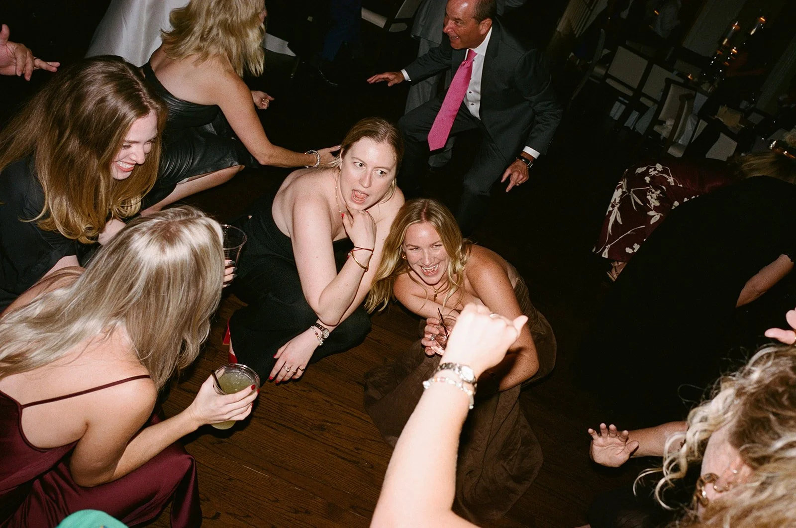 Candid 35mm film photograph of women dancing and celebrating on the wedding reception dance floor at Hinsdale Golf Club, captured by Chicago film wedding photographer Louie Abellera.