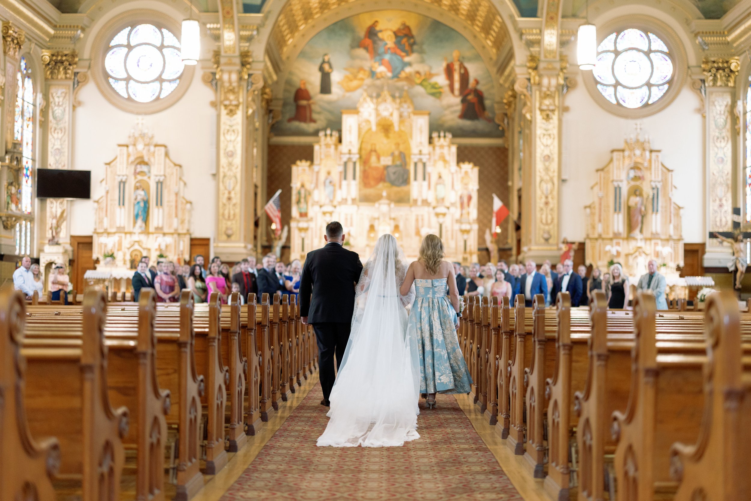 Wide shot of the newlywed couple walking back down the aisle beneath the church's painted ceiling