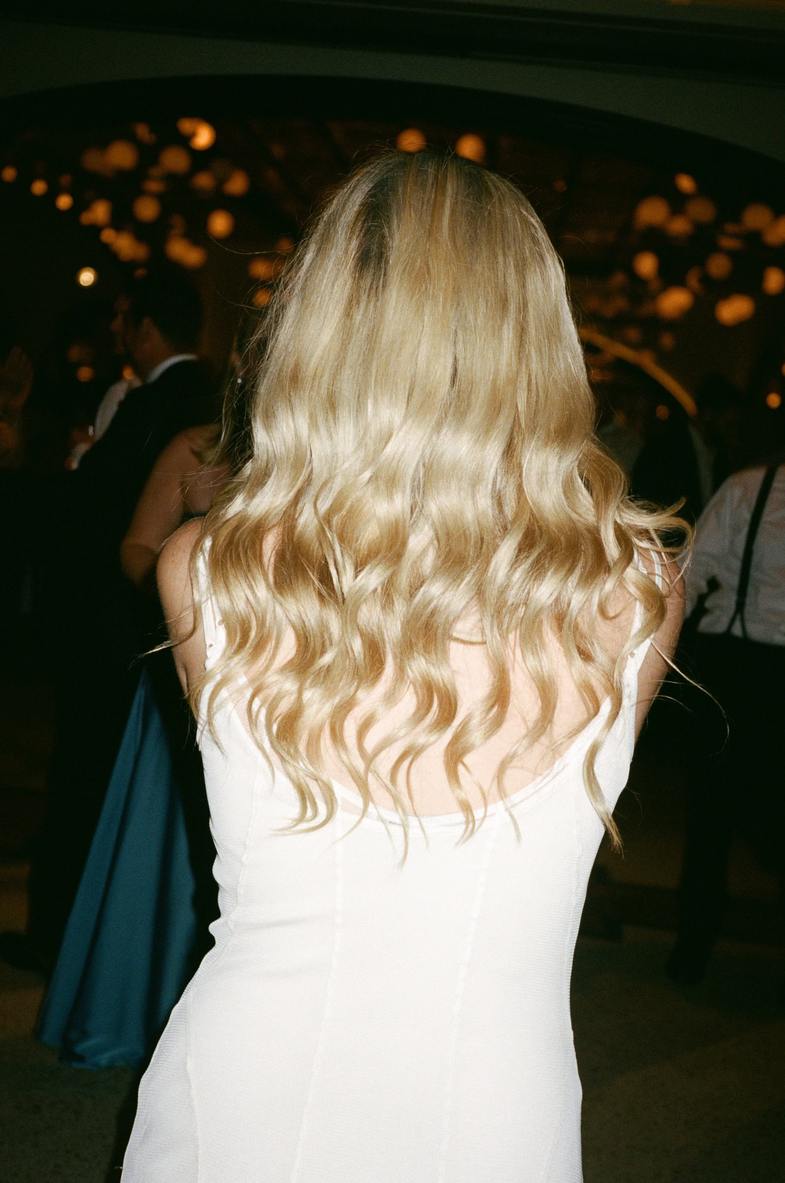 Detail shot of the bride's wavy blonde hair from behind on the dance floor