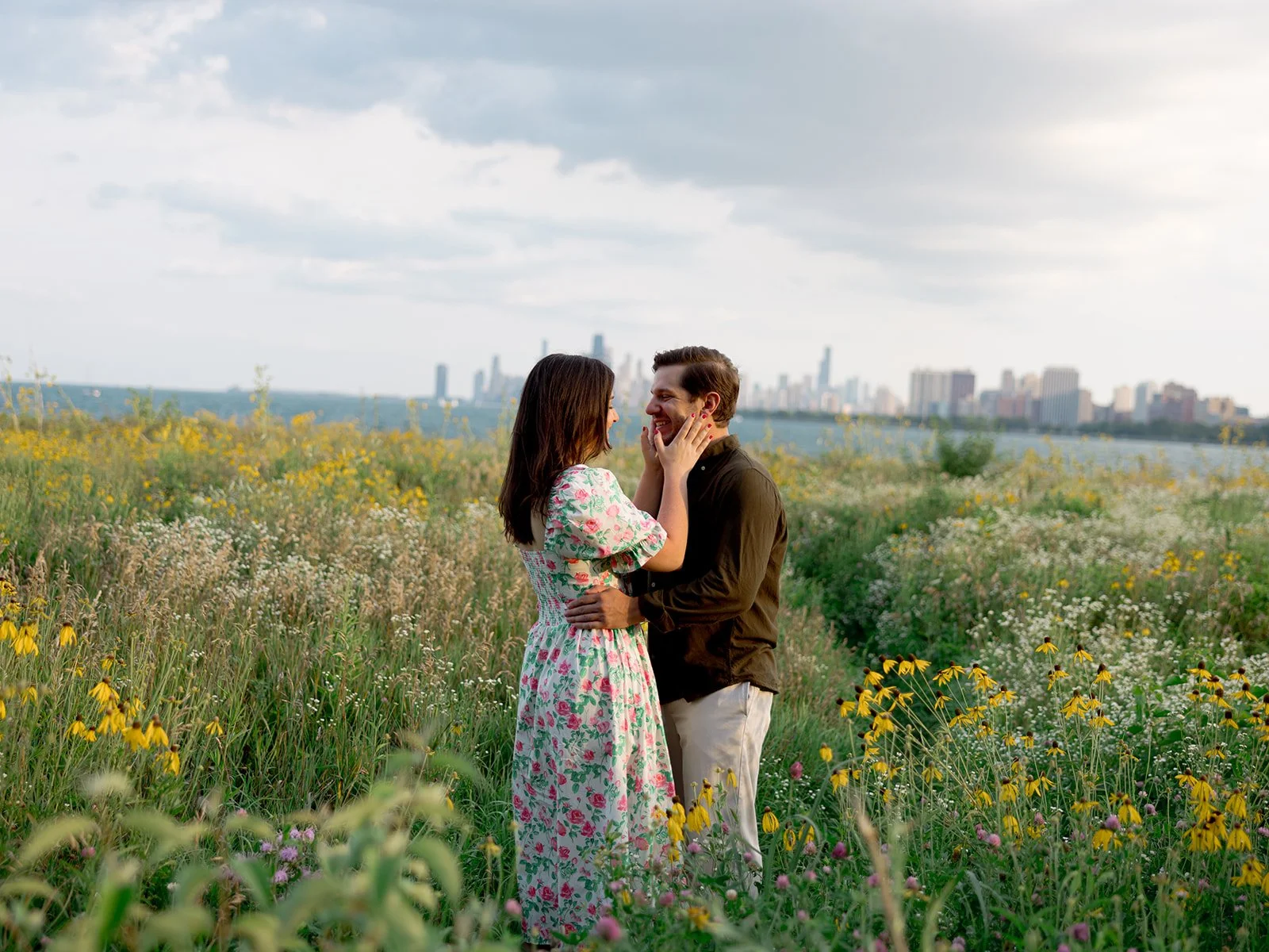 a couple embracing in a field in front of the chicago skyline