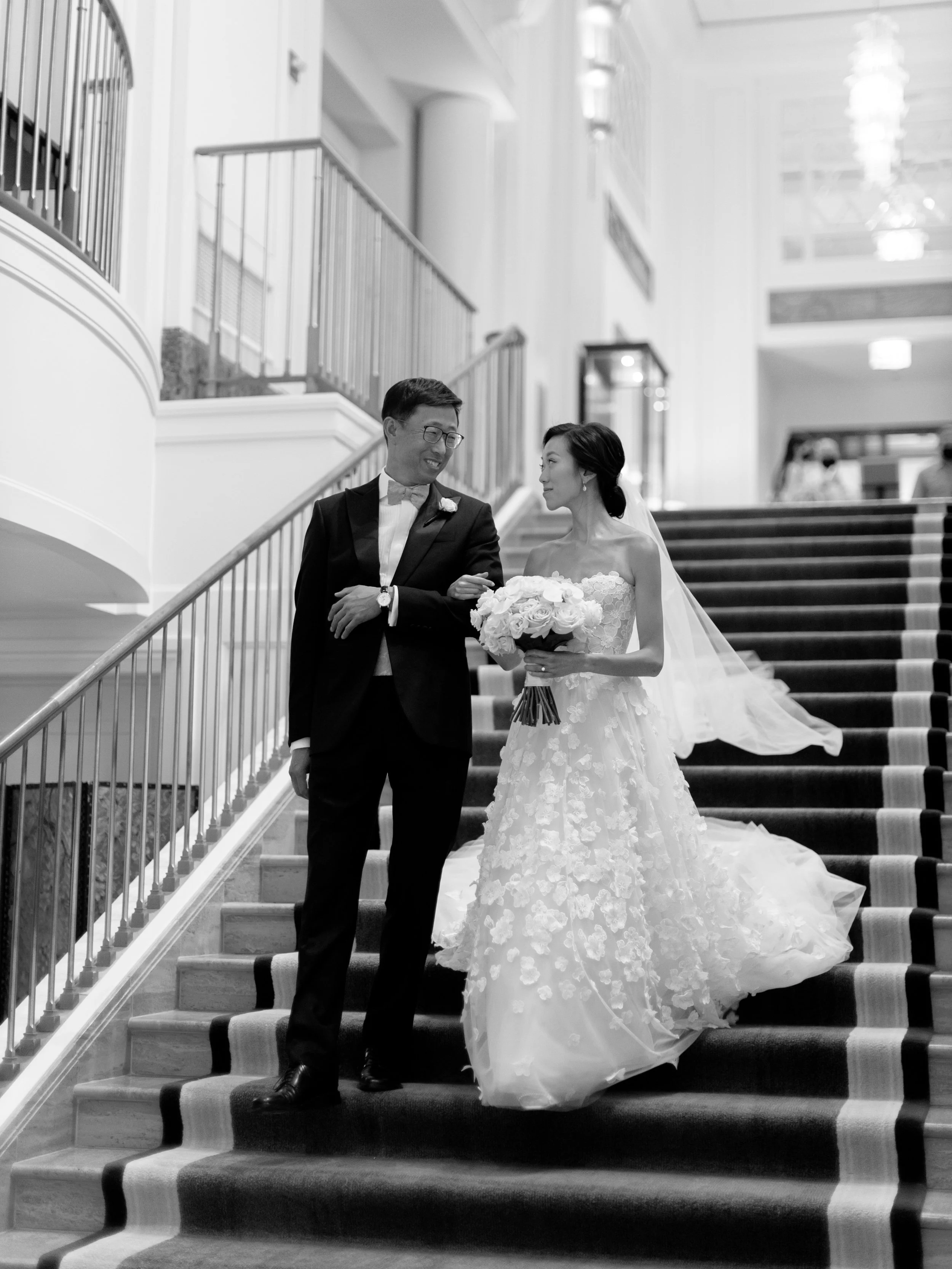 Black and white photograph of the bride and her dad descending the Peninsula Chicago grand staircase together