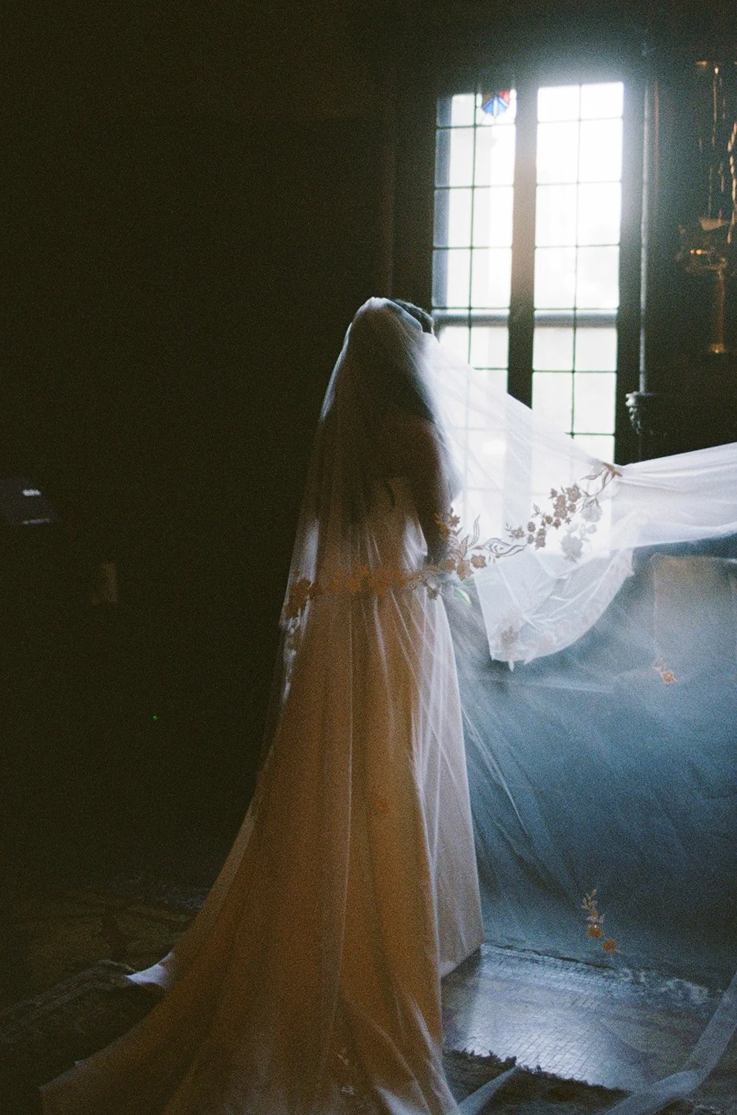 A dramatic overhead view of the bride's cathedral veil and lace-detailed train flowing across marble flooring. Shot on film by a Chicago film wedding photographer.