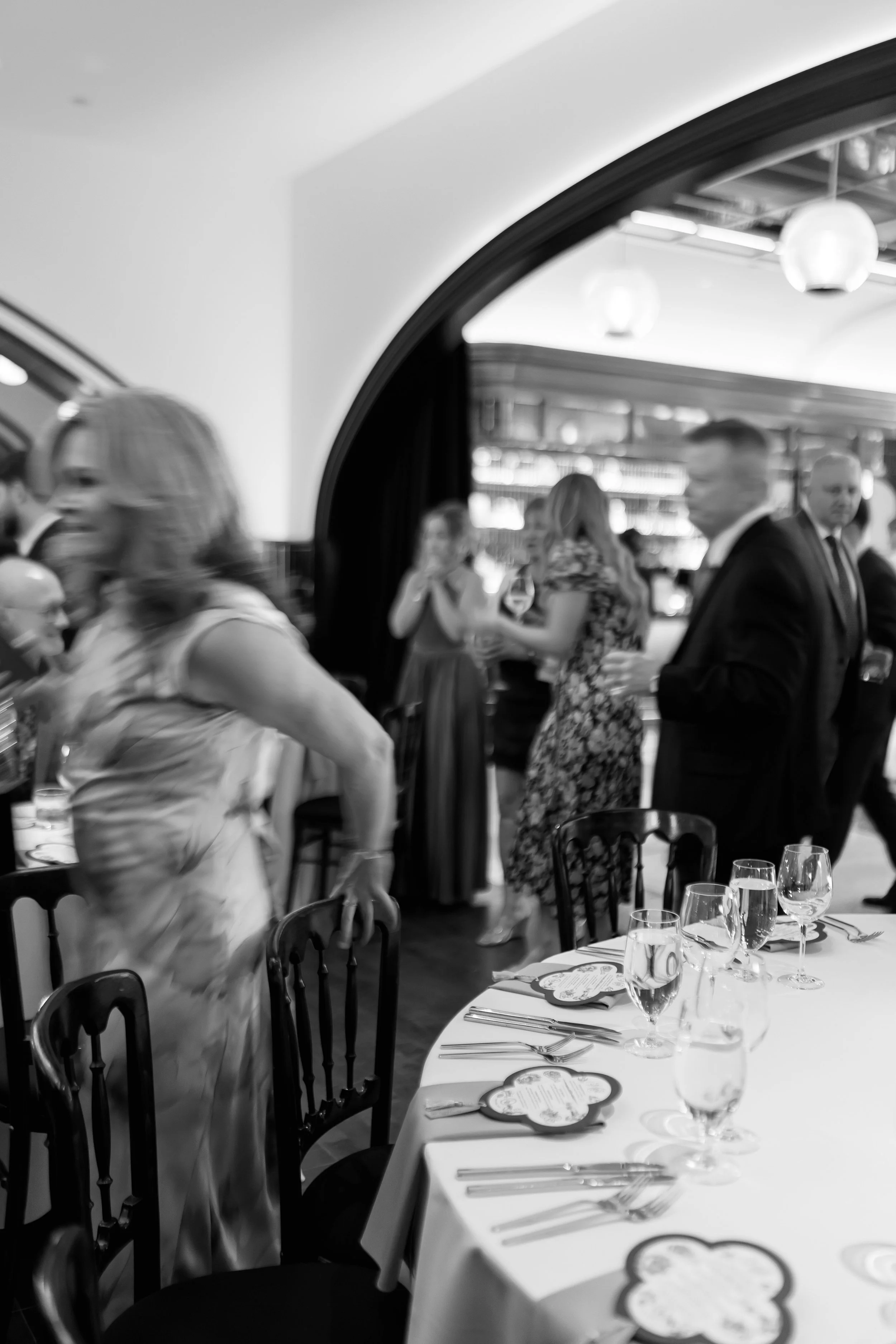 Black and white candid of a guest walking through an archway during cocktail hour