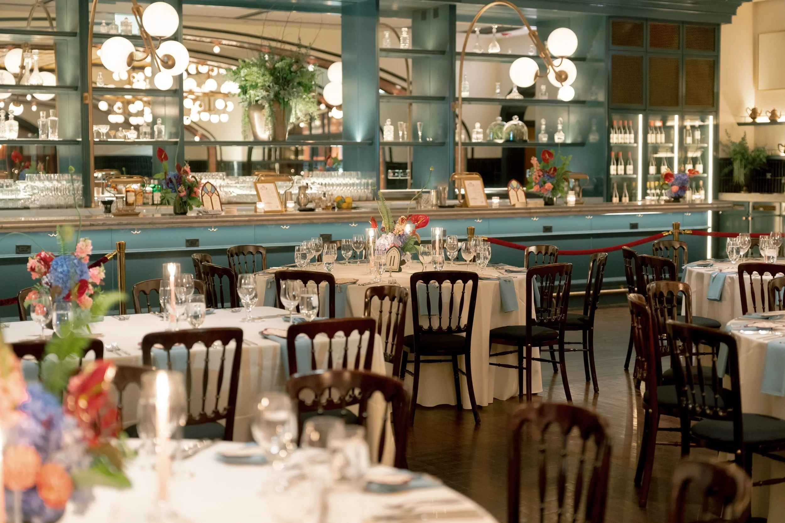 Wide shot of the reception dining room set with tables beneath string lights and arched mirrors