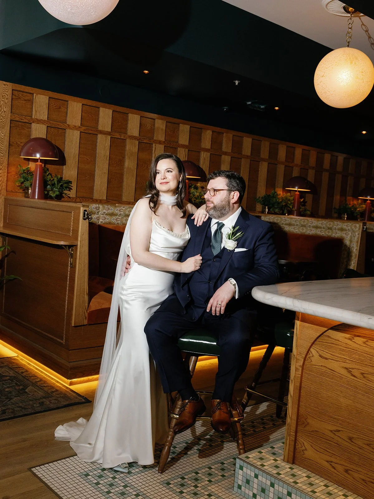 Film portrait of a bride in a silk gown and groom in a navy suit posing at the bar at Bisous in Chicago's West Loop, photographed by Chicago film wedding photographer Louie Abellera.