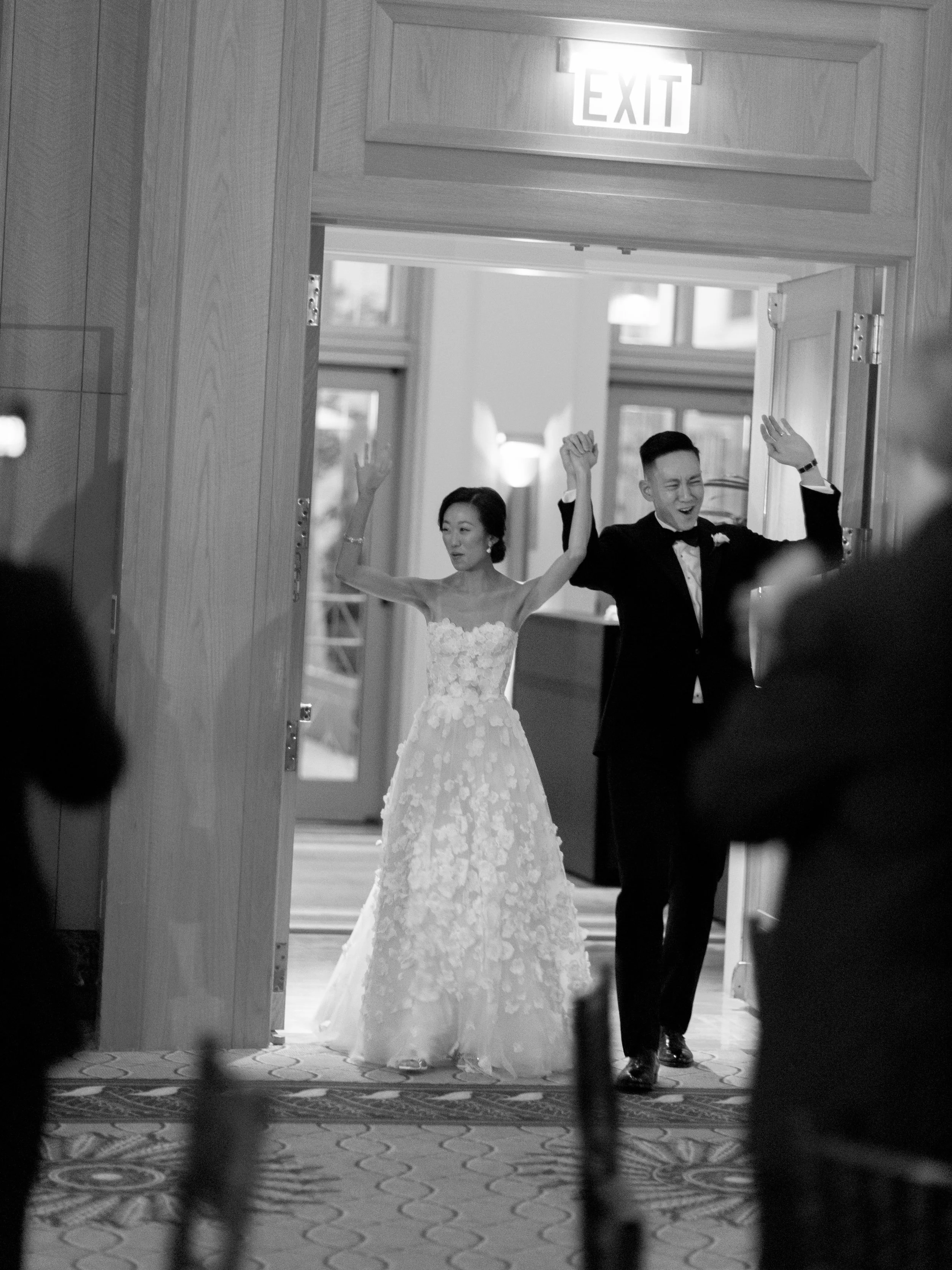 Black and white photograph of the bride and groom making their grand entrance into the Peninsula Chicago reception