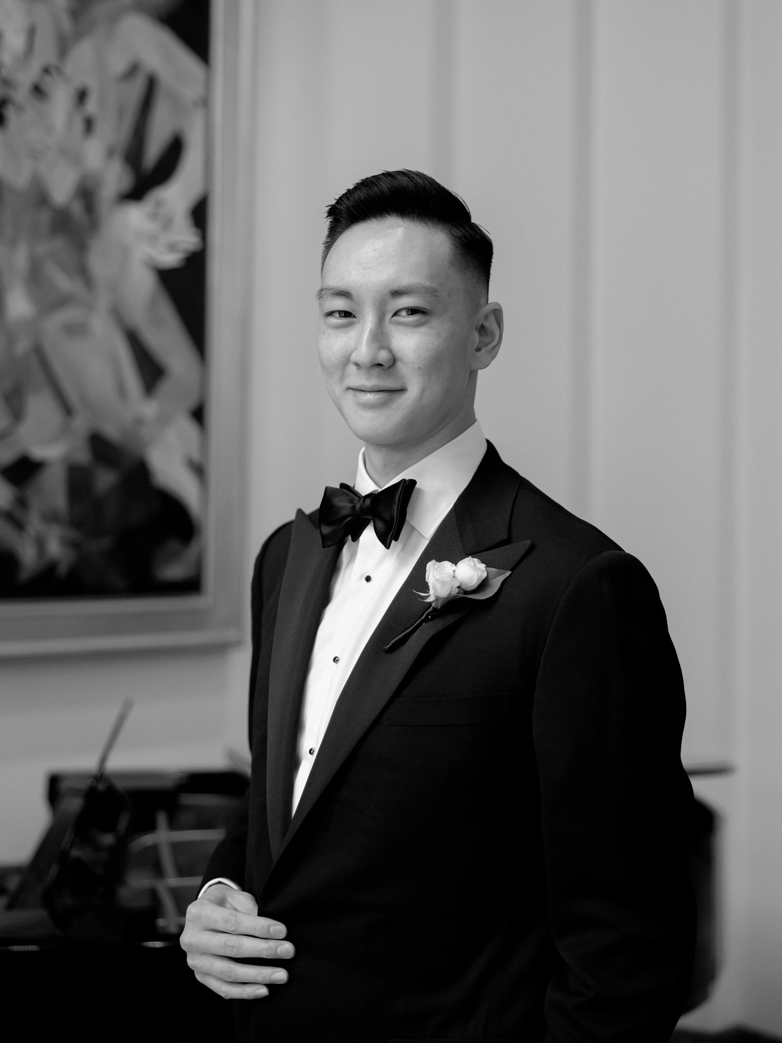 Black and white film portrait of the groom in a black tuxedo and white rose boutonniere at The Peninsula Chicago