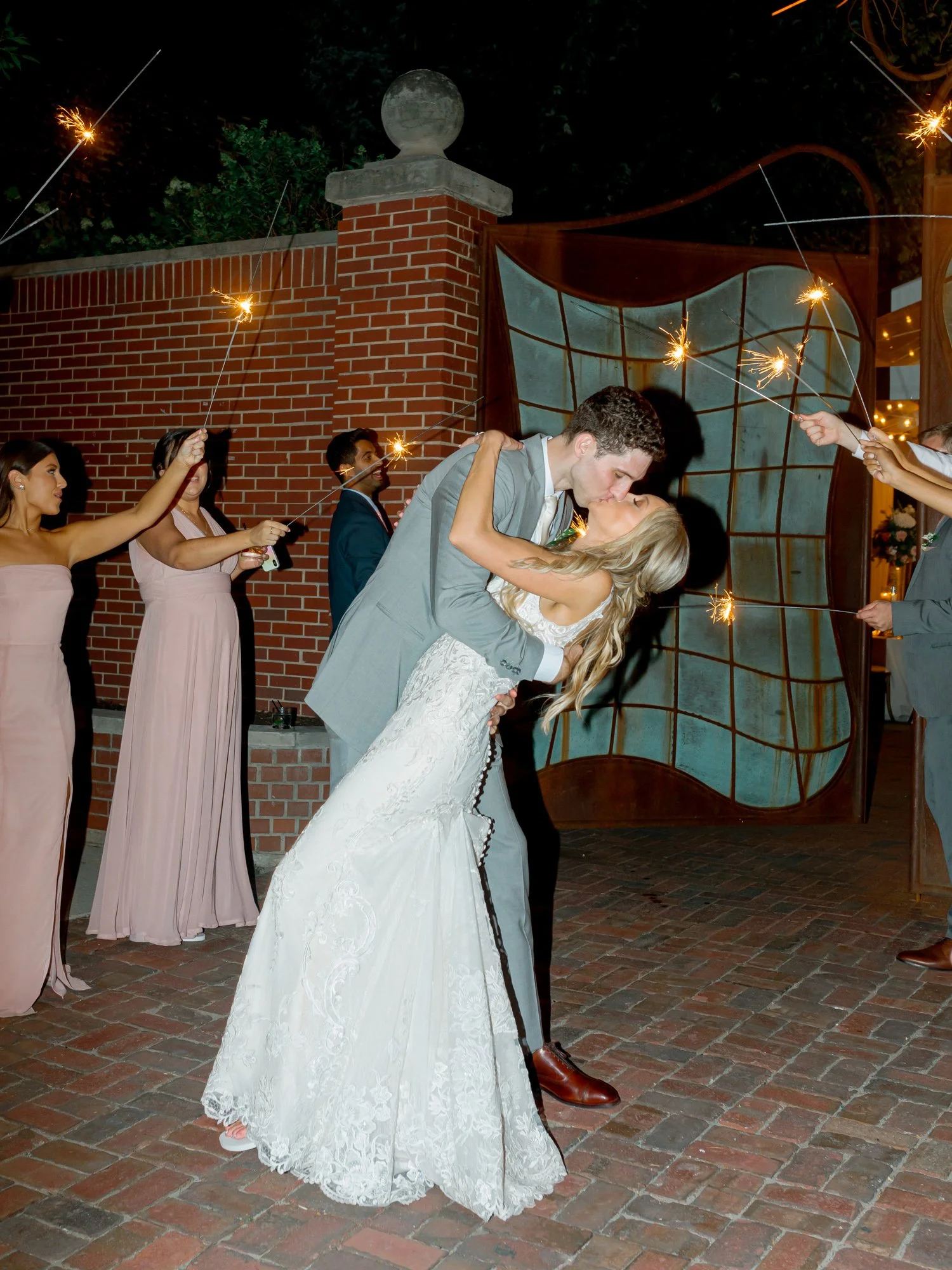 The bride and groom share a dramatic dip-kiss beneath a shower of sparklers during their nighttime sendoff at the Chicago Illuminating Company.