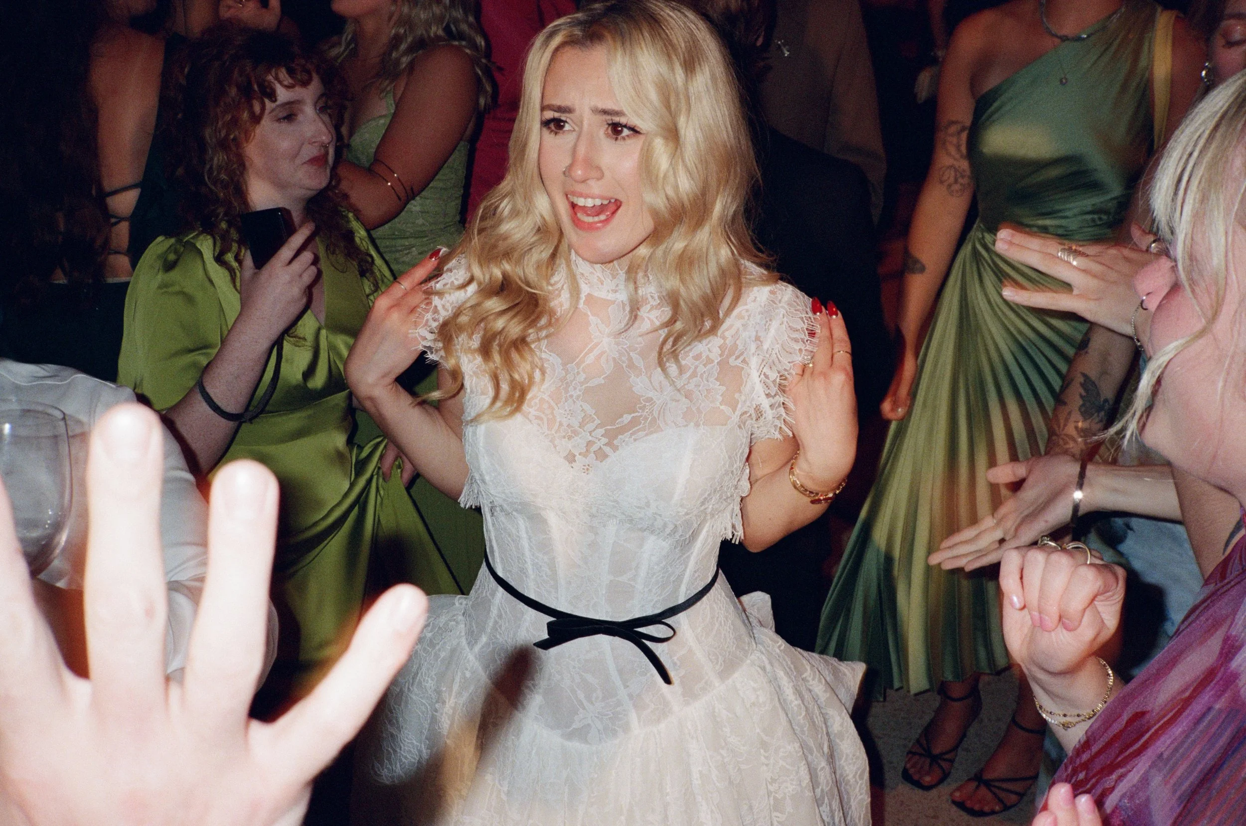 Bride dances with an emotional, joyful expression as guests surround her