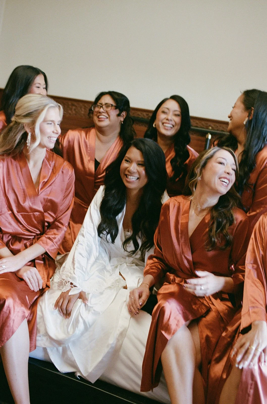 Bridesmaids in silky coral robes with the bride during getting ready at Chicago Athletic Association. Shot on film by a Chicago wedding photographer.
