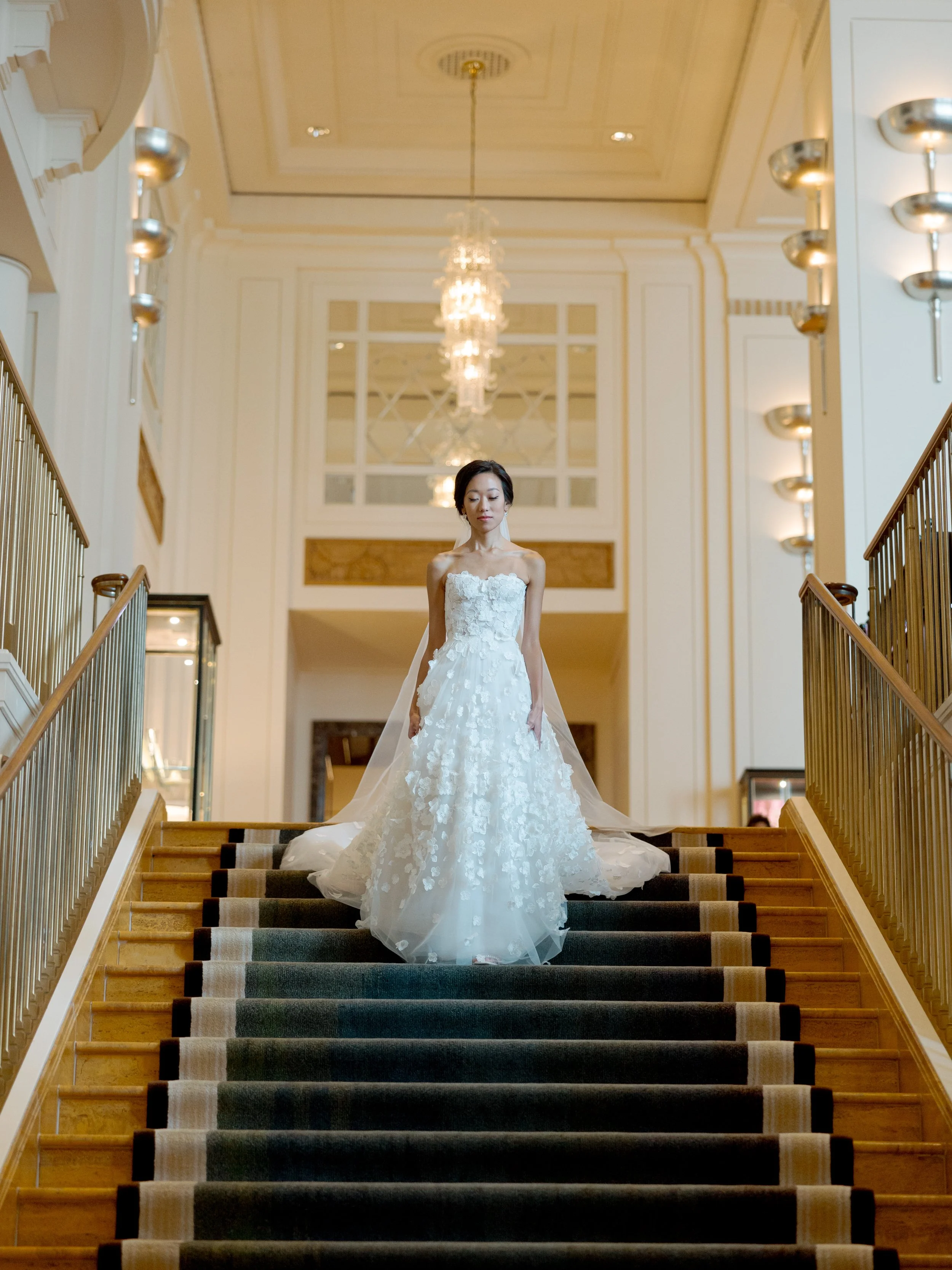 Film bridal portrait of the bride descending the Peninsula Chicago grand staircase beneath a crystal chandelier