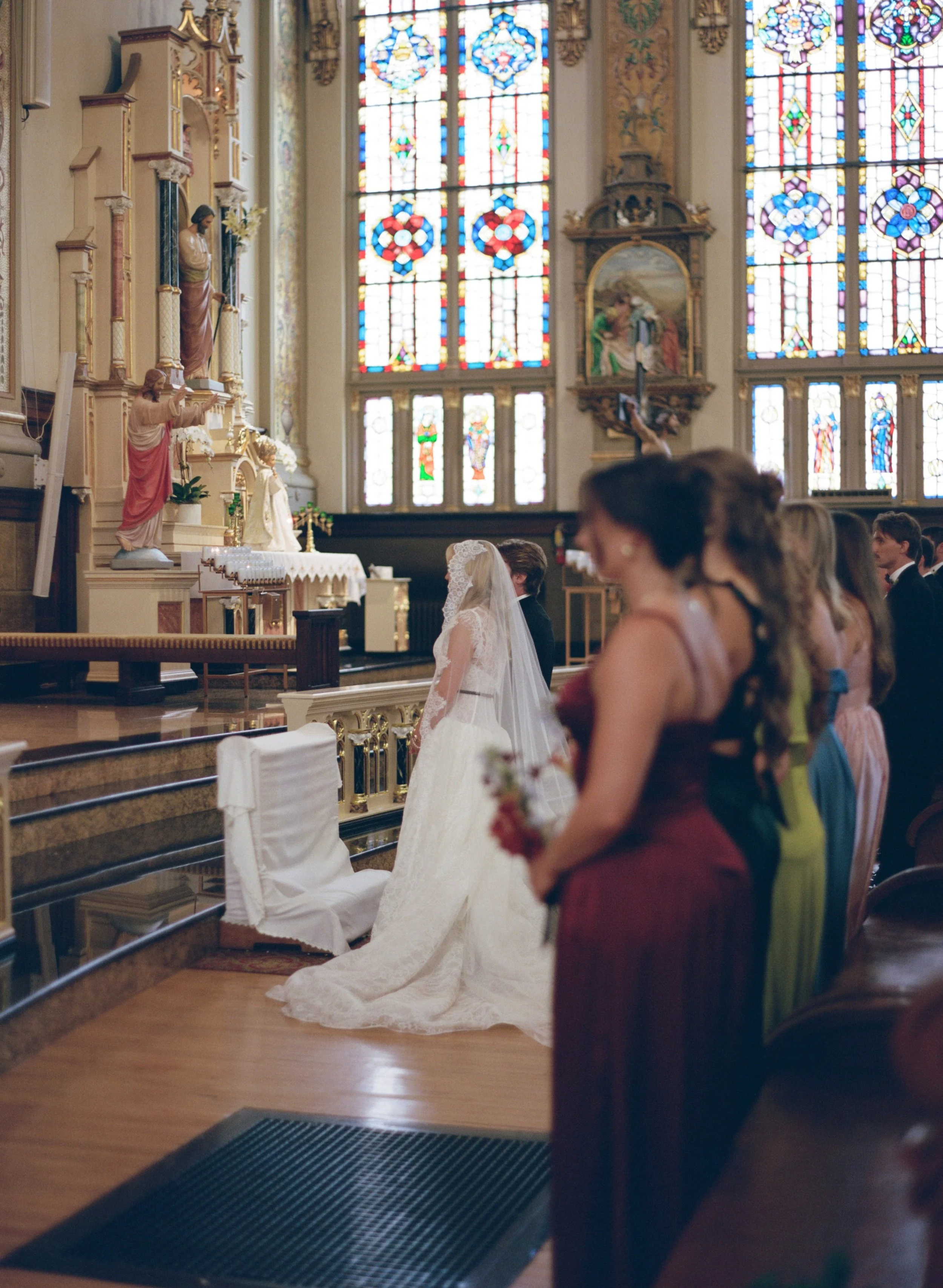 Bridesmaid walks down the aisle past the church's colorful stained glass windows