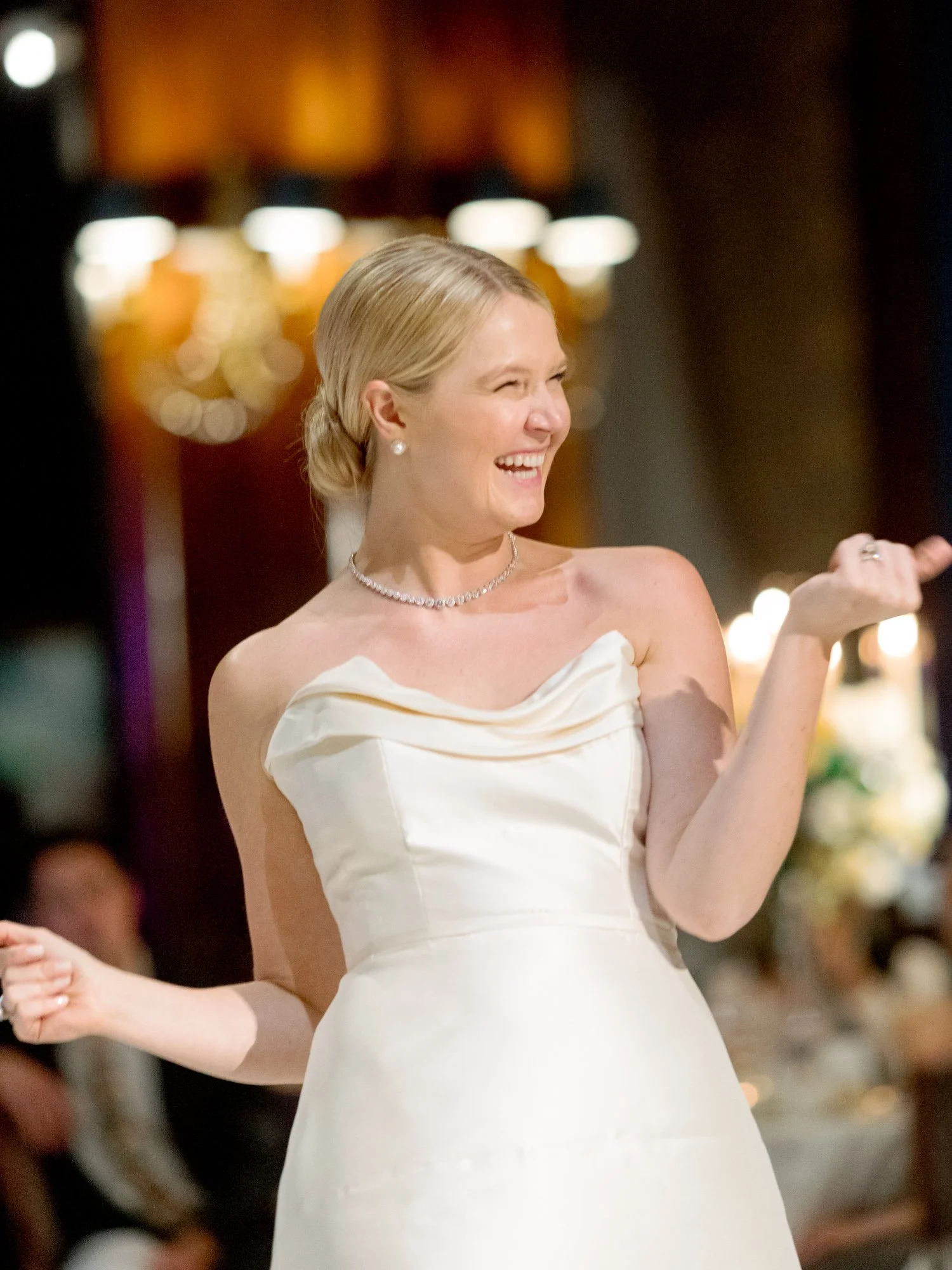 A radiant close-up of the bride mid-dance in her strapless silk gown, diamond necklace catching warm light at the Union League Club Chicago reception.