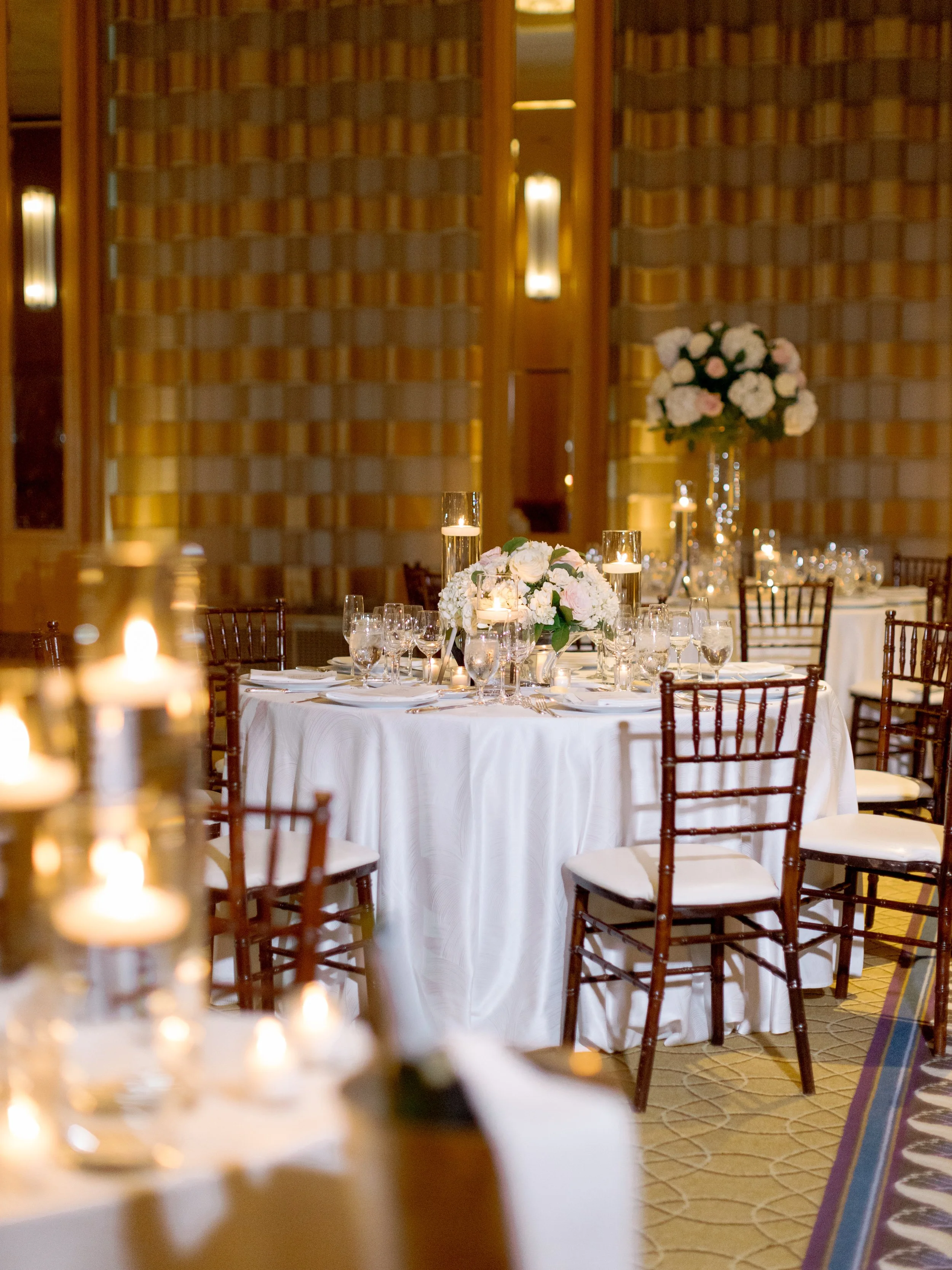 Film reception detail of round tables with chiavari chairs, candles and rose centerpieces at The Peninsula Chicago