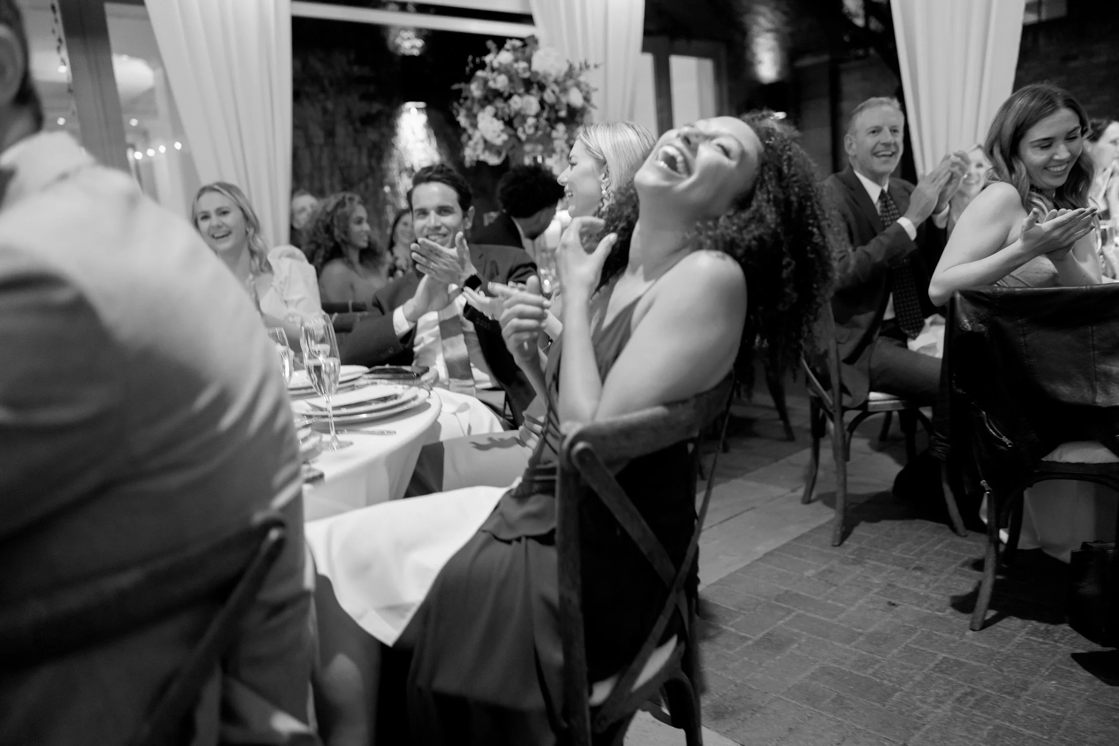 Guests burst into laughter during the speeches at the Chicago Illuminating Company reception in this energetic black-and-white candid shot, joy everywhere.