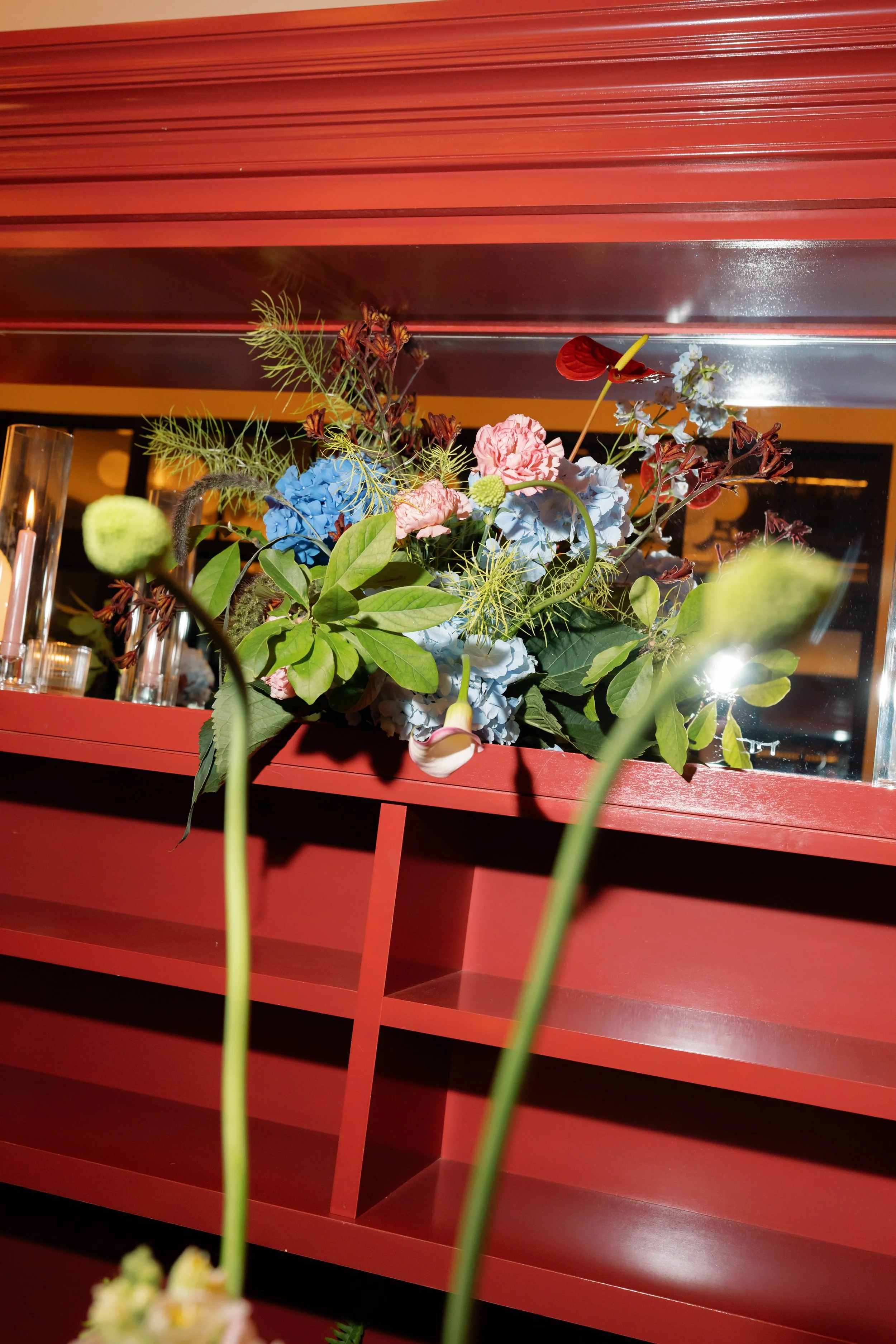 Hydrangea and anthurium floral arrangement styled on a red bar shelf