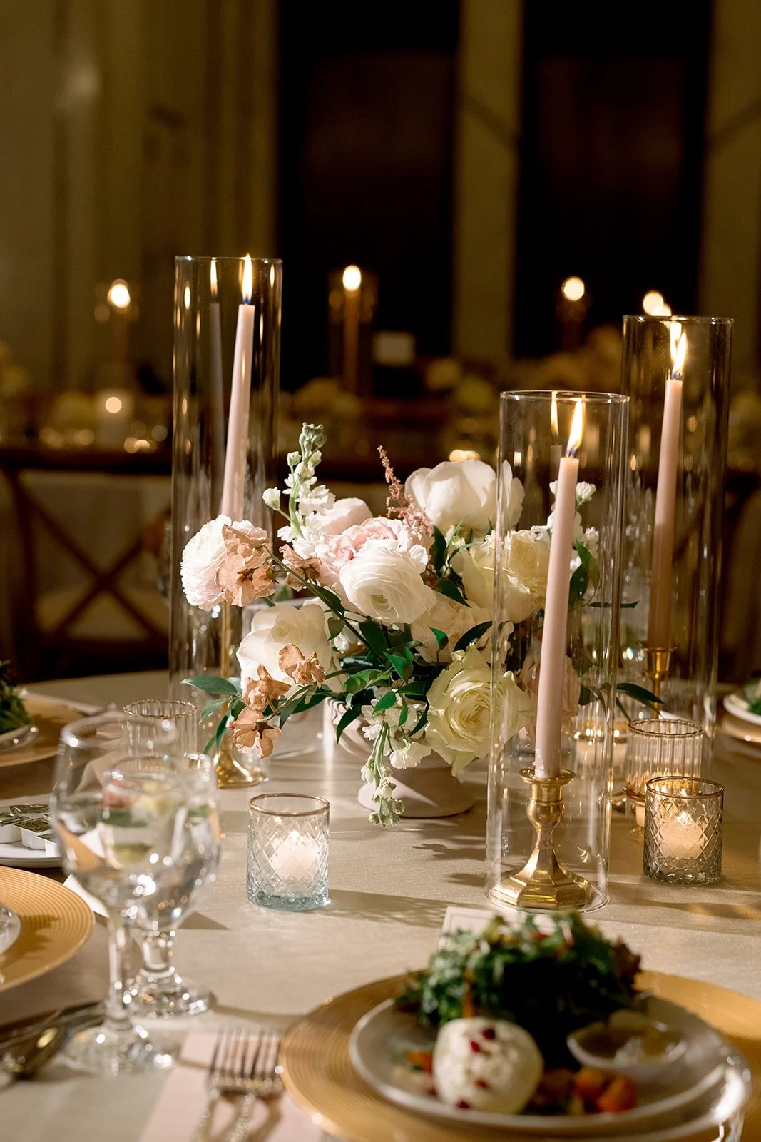 A lush floral centerpiece with white and blush garden flowers mixed with greenery and surrounded by taper candles. Shot on film by a Chicago wedding photographer.