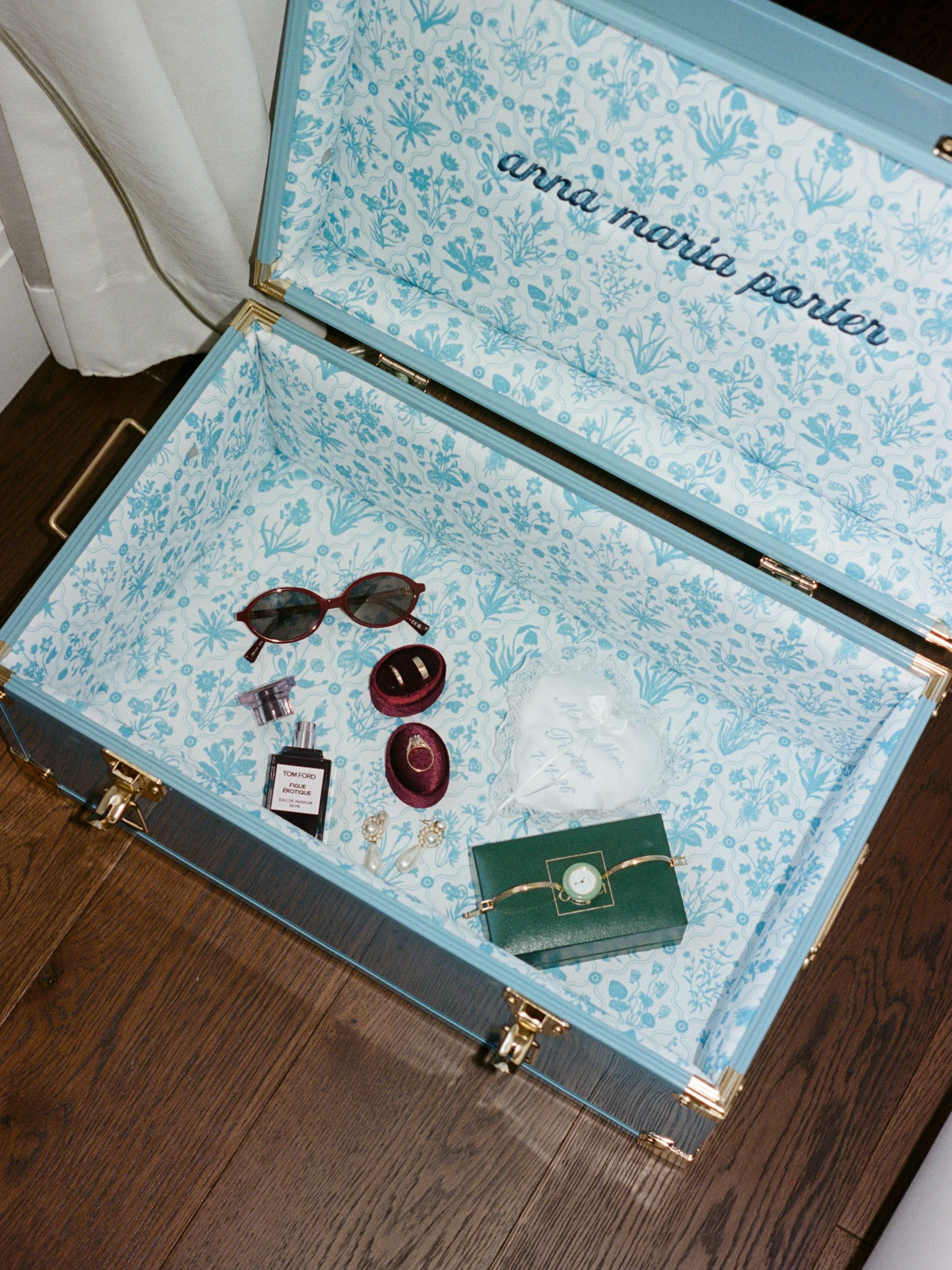 Sunglasses, perfume, and jewelry laid out inside the monogrammed vintage trunk