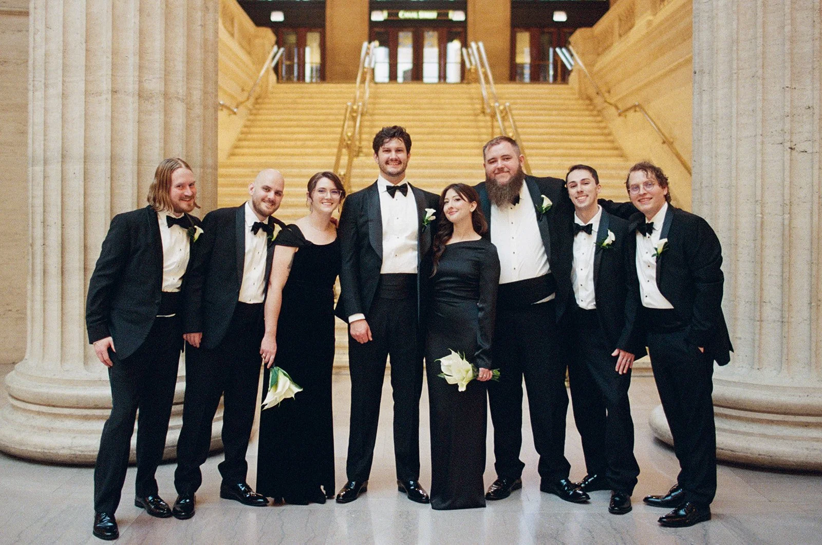 Brennan with his groomsmen all in black tie and tuxedos posed on Union Station's architectural grand staircase. Shot on film by a Chicago wedding photographer.