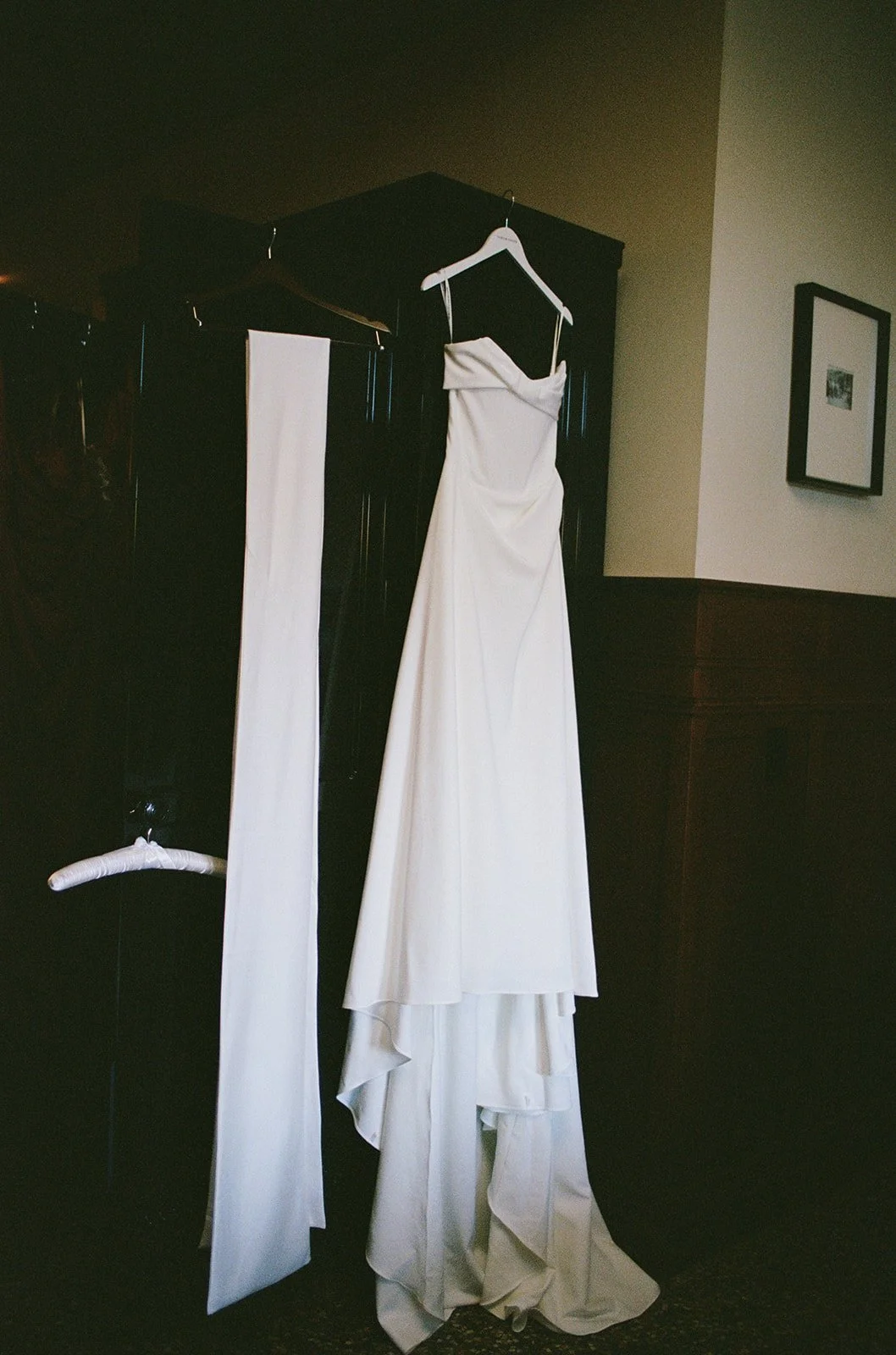The bride's white dress carefully hung and displayed in the getting ready suite at Chicago Athletic Association. Shot on film by a Chicago wedding photographer.