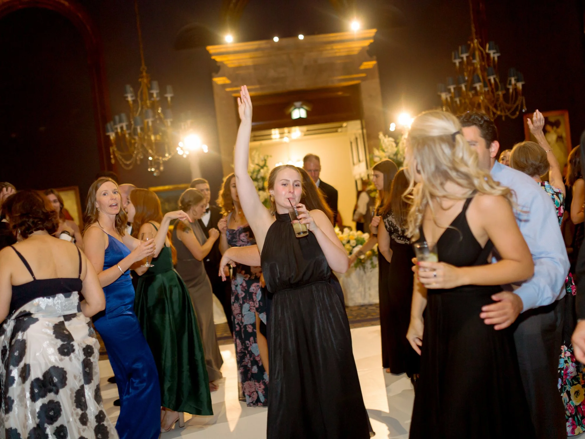 Guests in formal attire dance with arms raised inside the Union League Club grand ballroom, candid and joyful in one of Chicago’s finest reception rooms.