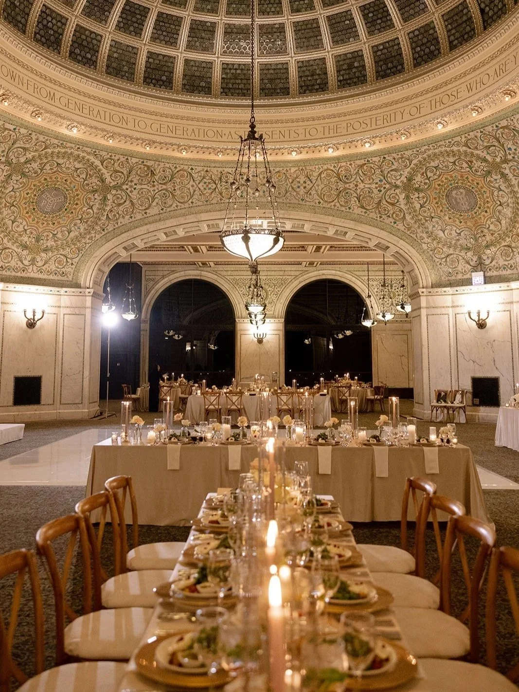 Long reception tables beautifully set for dinner with candlelight in the grand hall at Chicago Cultural Center. Shot on film by a Chicago film wedding photographer.