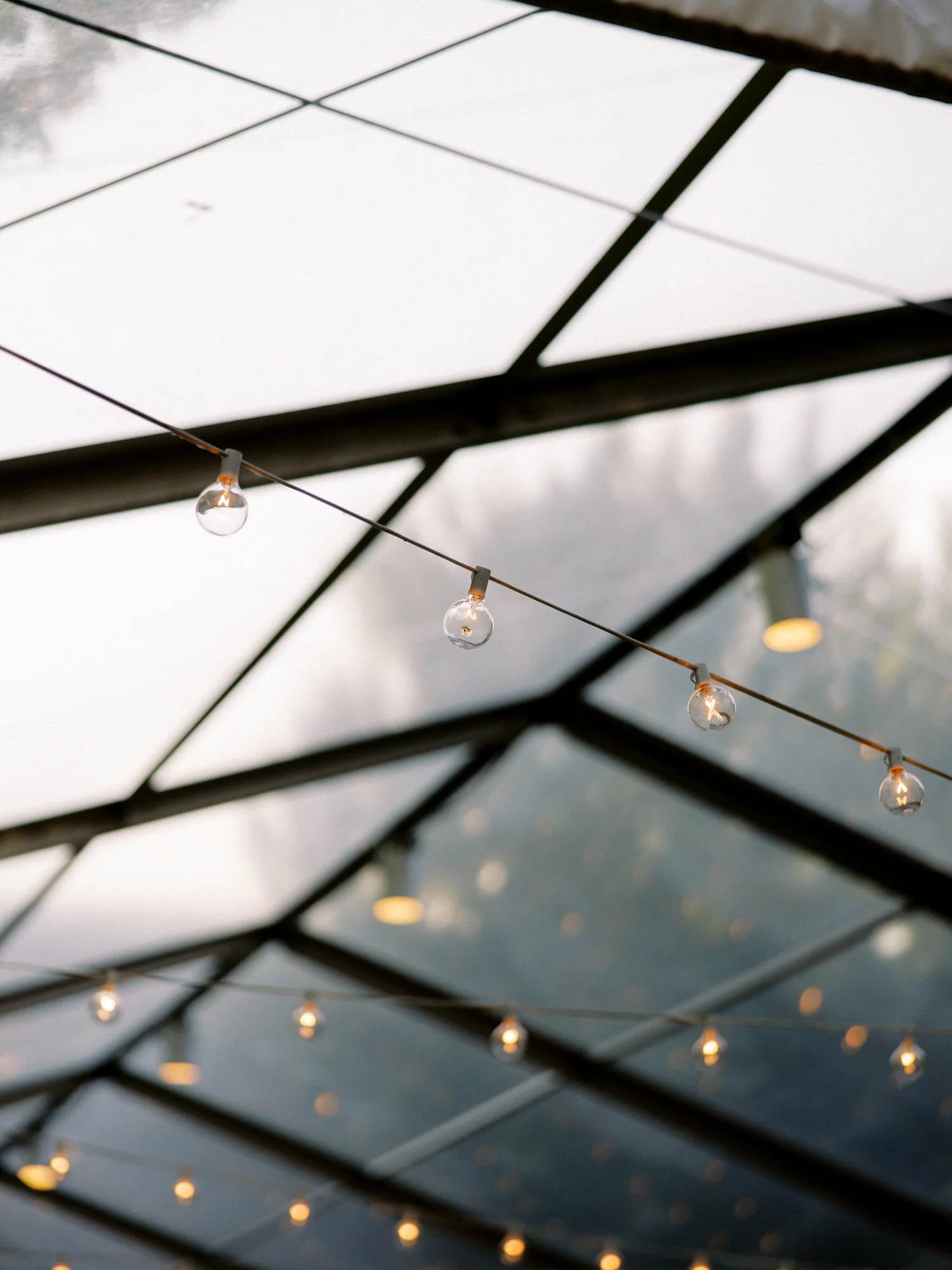 Warm globe string lights dangle from the geometric glass-paneled roof of the Chicago Illuminating Company, casting a dreamy golden glow across the venue.