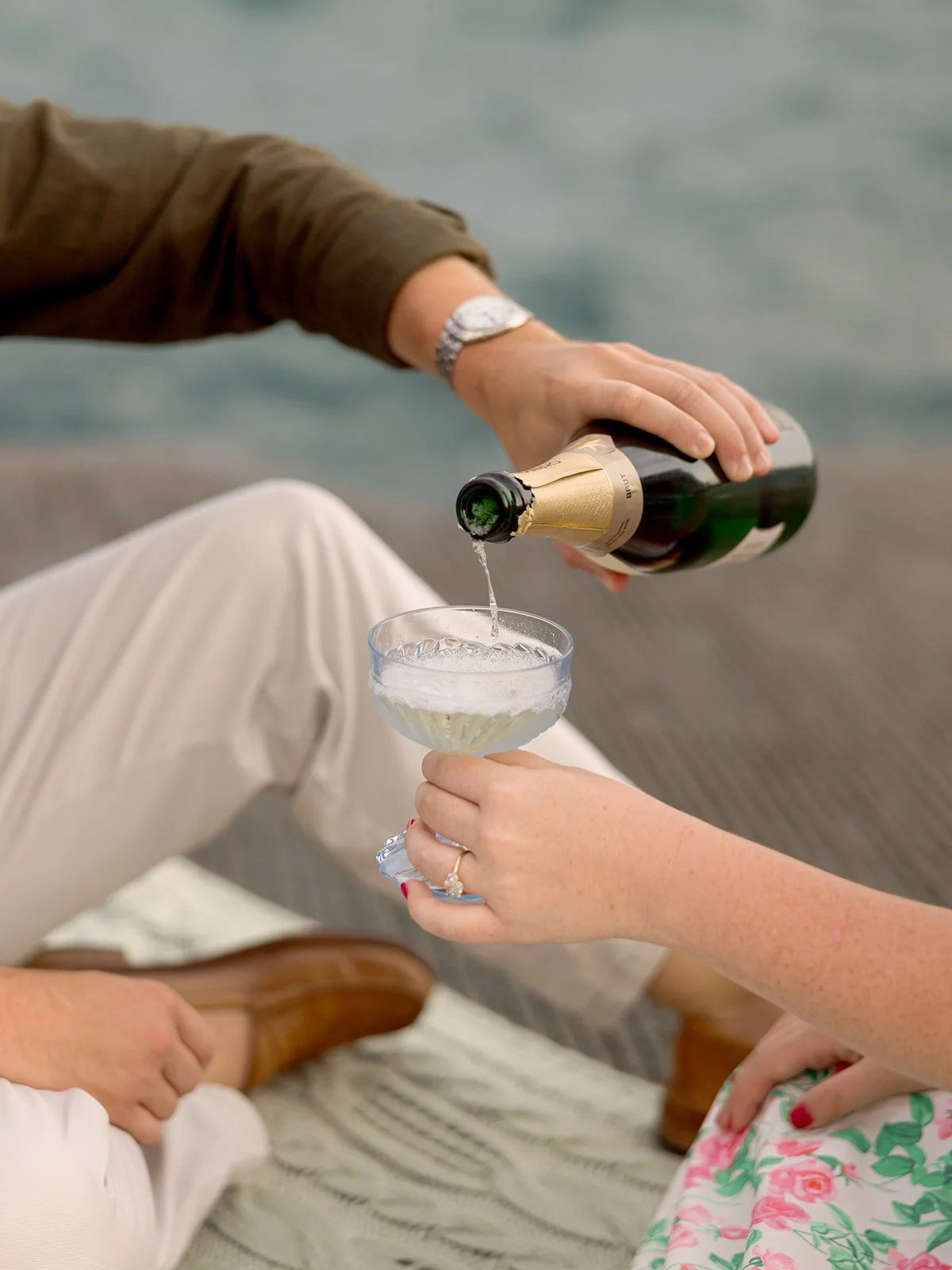 a man pouring wine for his fiance on lake michigan