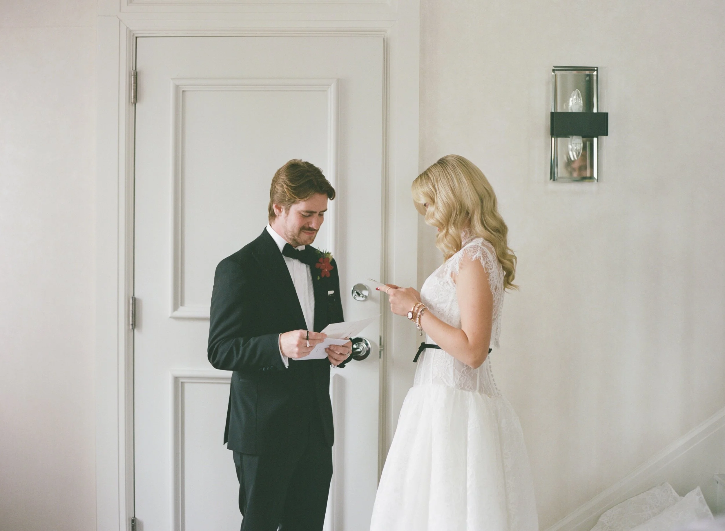 Bride and groom smile while reading handwritten vow letters to each other before the ceremony