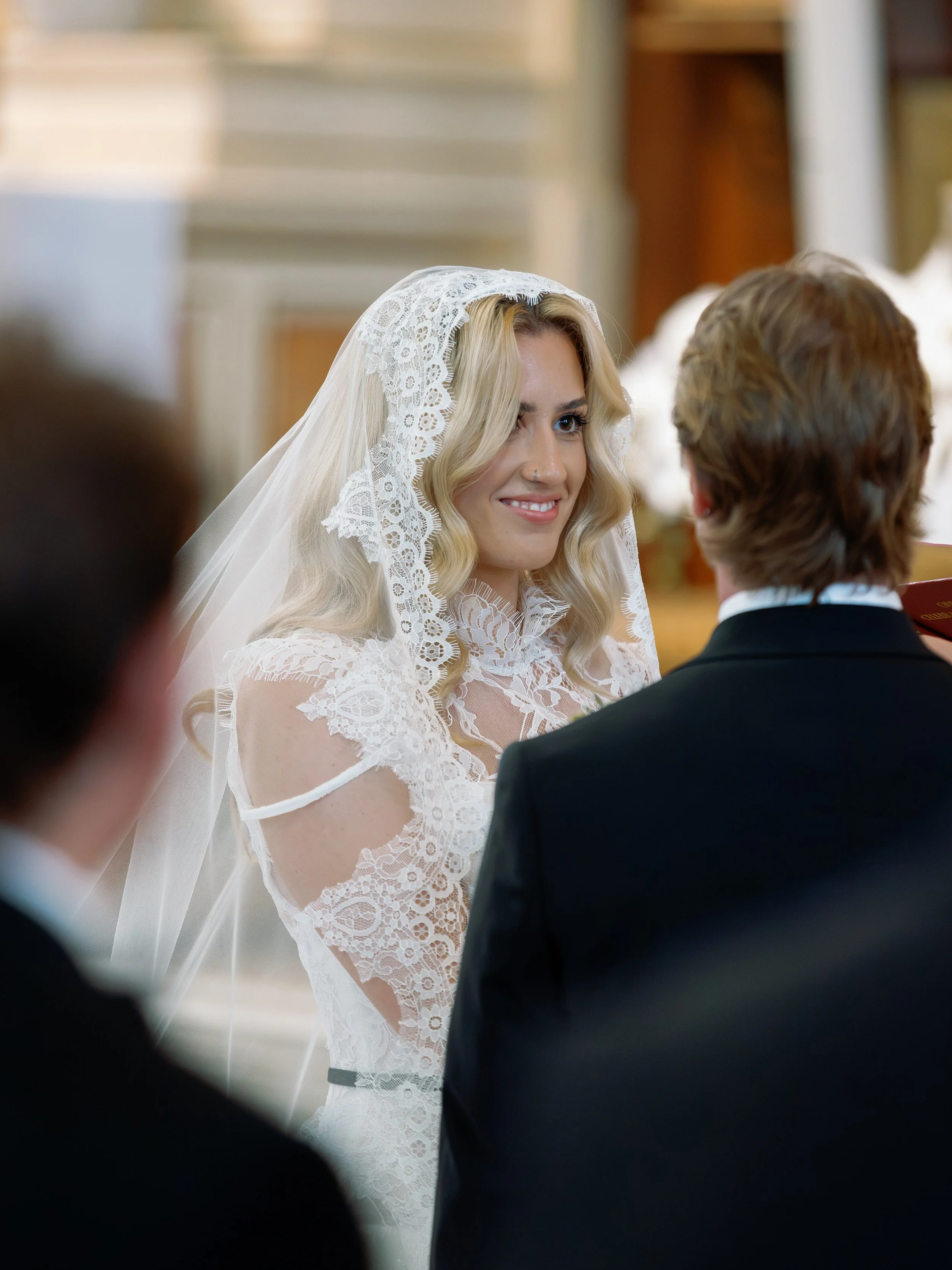 Bride glances over at the groom during the ceremony, her lace veil framing her face