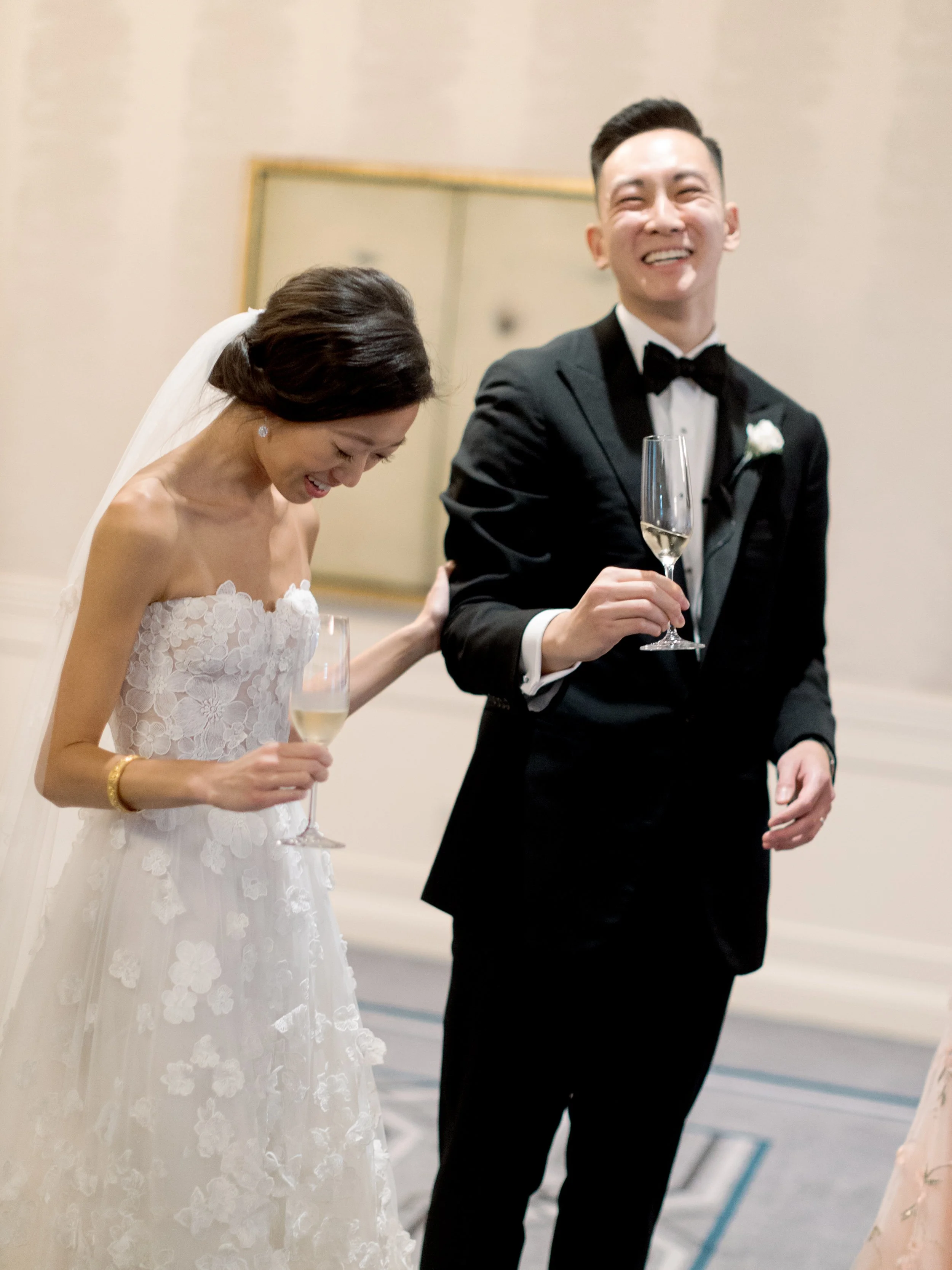 Film photograph of the bride and groom laughing together with champagne flutes at The Peninsula Chicago wedding