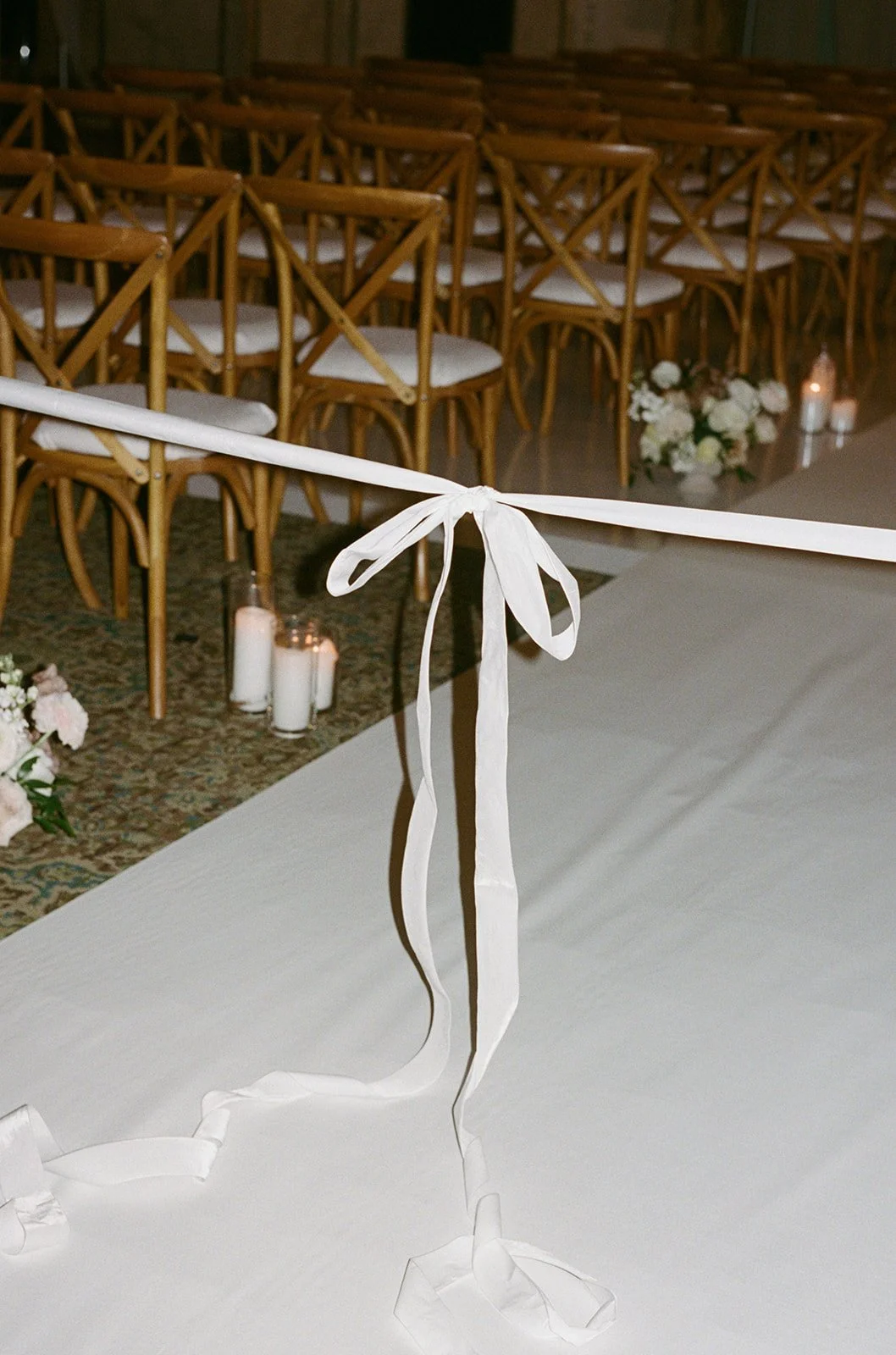 Ceremony seating at Chicago Cultural Center with wooden chairs decorated with white ribbon bows and floral arrangements. Shot on film by a Chicago wedding photographer.