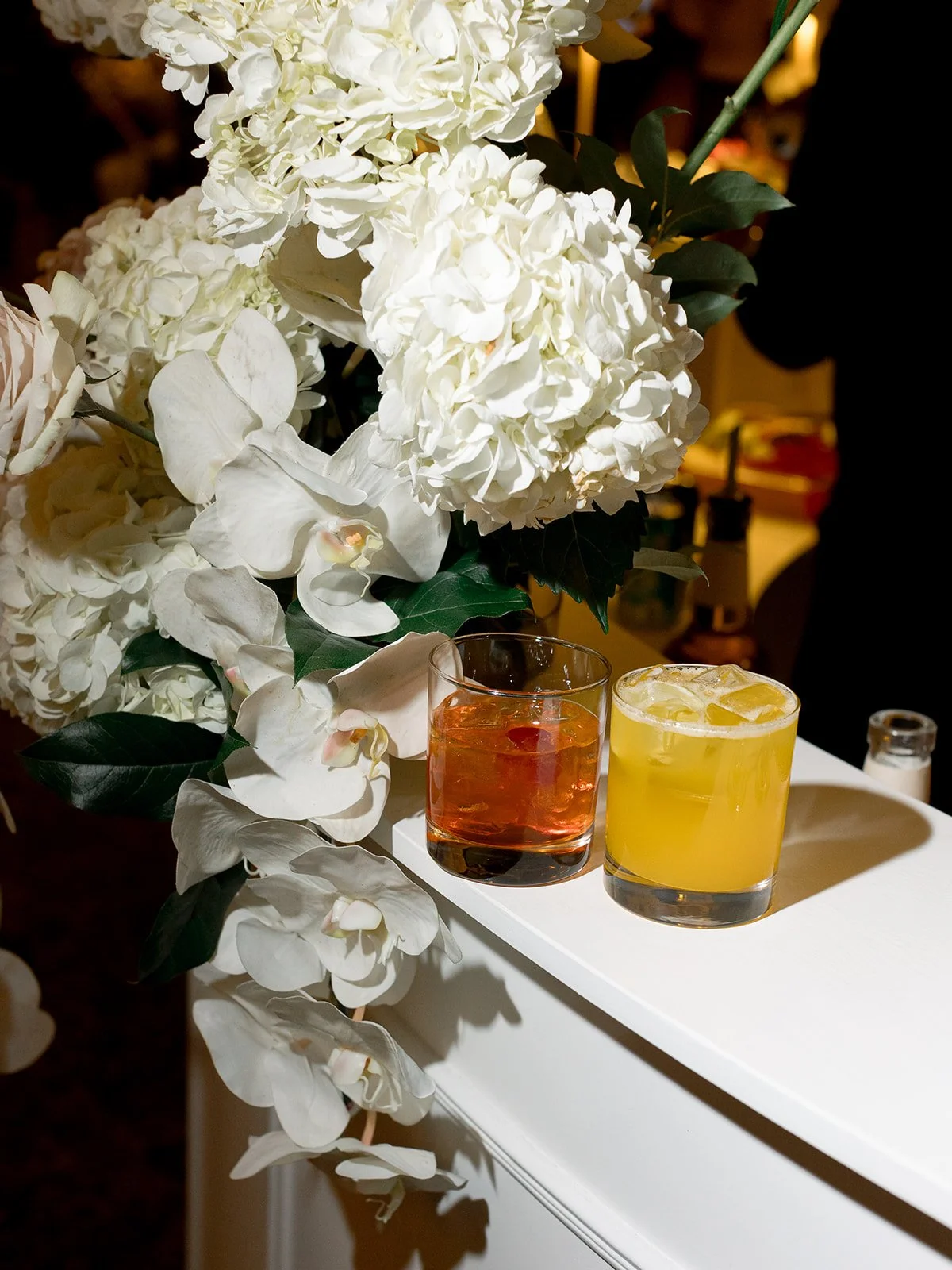 Cocktail bar detail featuring fresh white hydrangeas, amber and yellow signature drinks in elegant glassware. Perfect for a luxury wedding reception. Shot on film by a Chicago wedding photographer.
