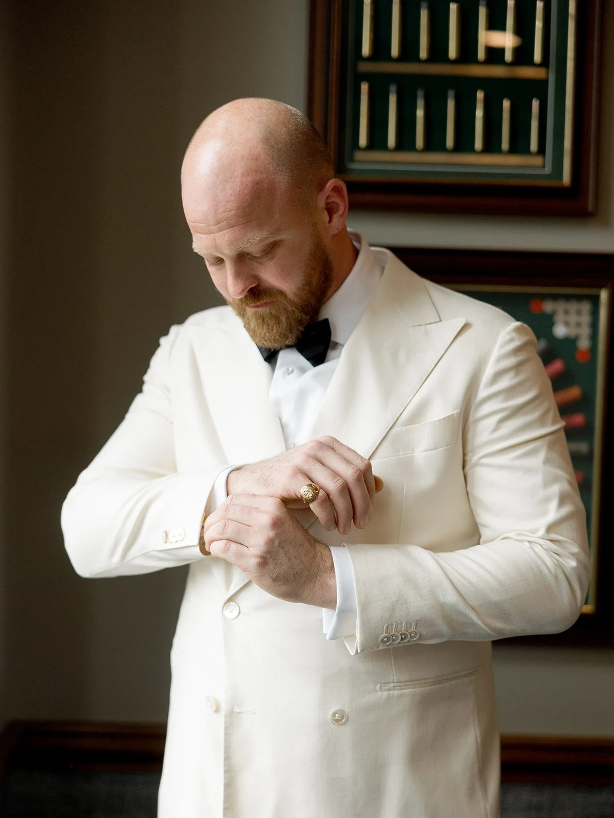 The groom steadies himself in a quiet getting-ready moment — adjusting the lapel of his white double-breasted dinner jacket, gold ring catching the light. Still, focused, almost meditative — captured by a Chicago film wedding photographer.