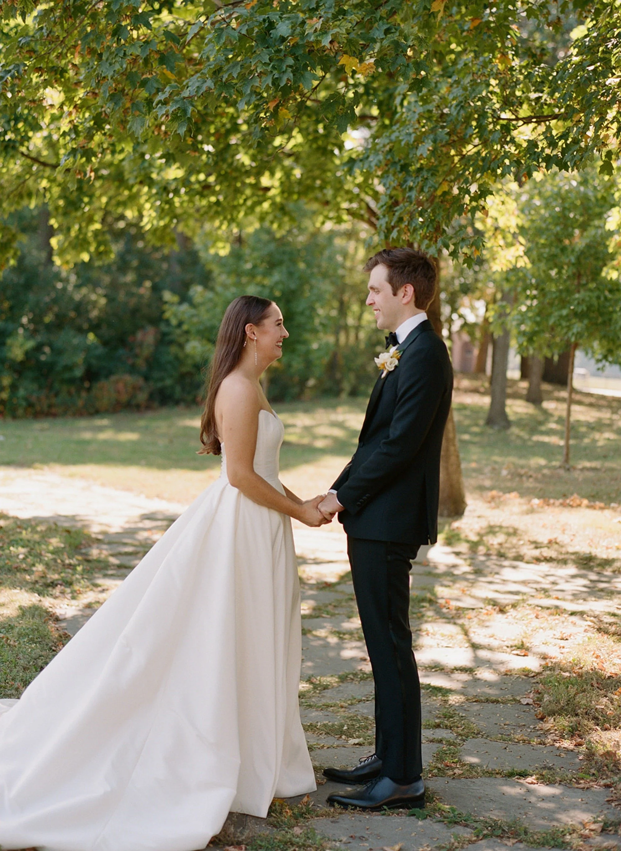 The first look — the couple faces each other and holds hands in the garden for the very first time on their wedding day, golden-hour light wrapping them in warmth. Columbus Park Refectory, Chicago film wedding photographer.
