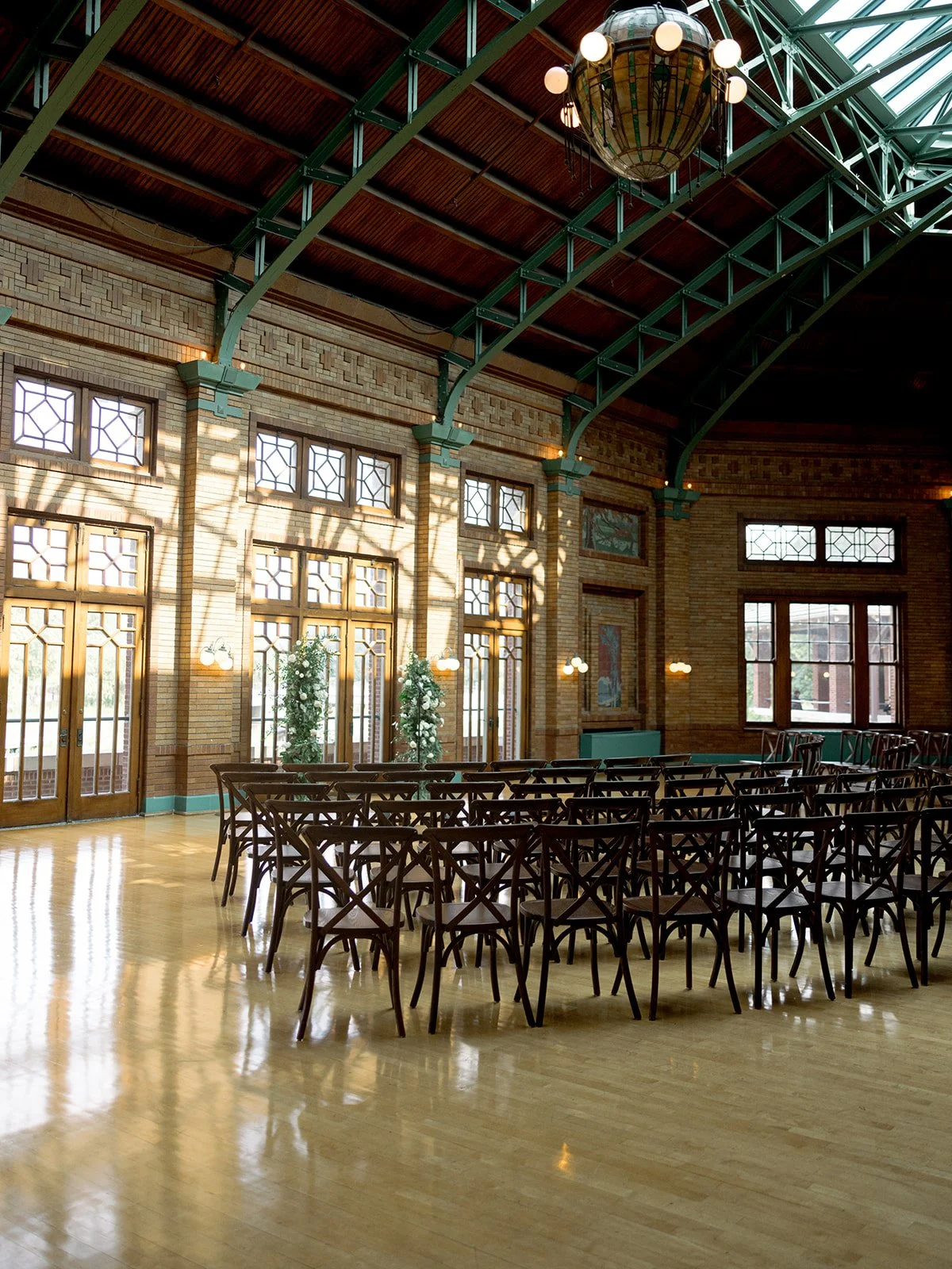 Cafe Brauer Great Hall set for the ceremony — rows of cross-back chairs, sunlight streaming through windows and the skylight ceiling.