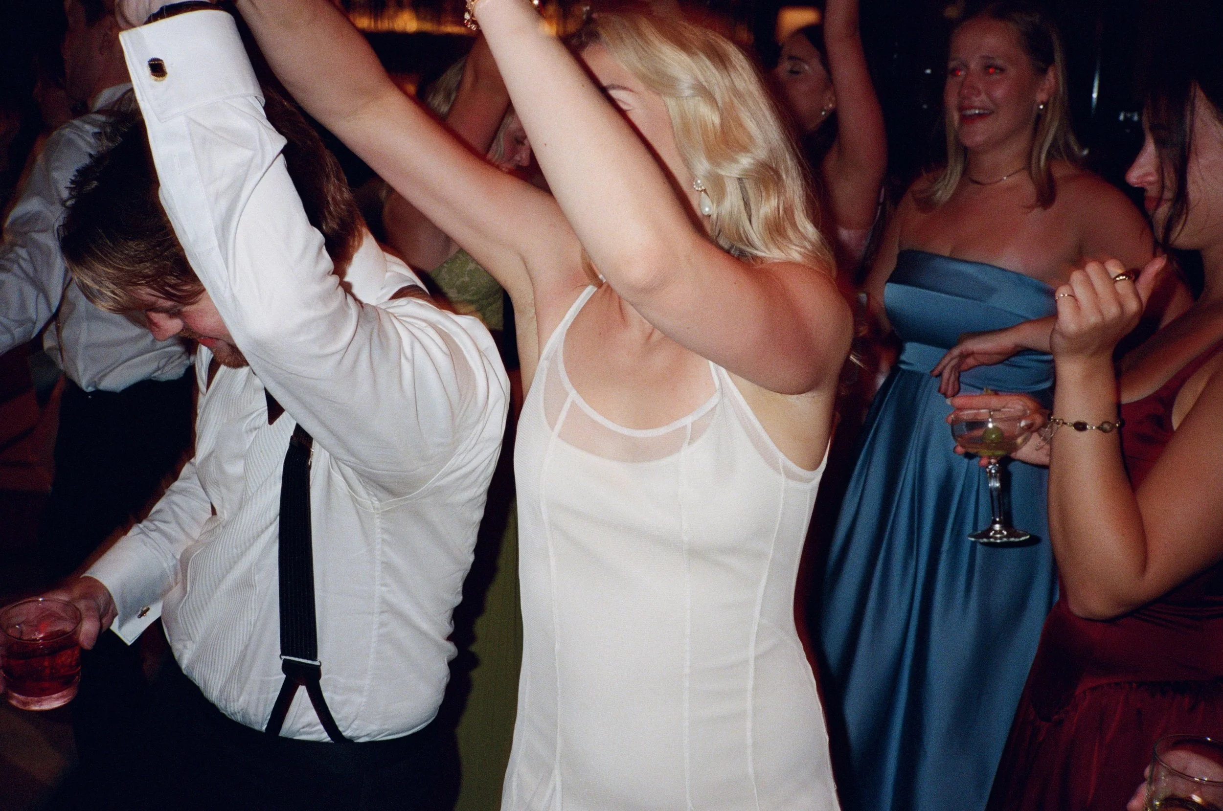 Guests dance with arms raised on a lively reception dance floor
