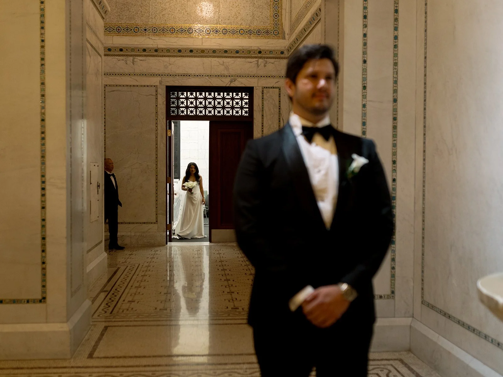 A candid of Sarah with her dad, and Brennan in the foreground as they prepare to walk down the aisle