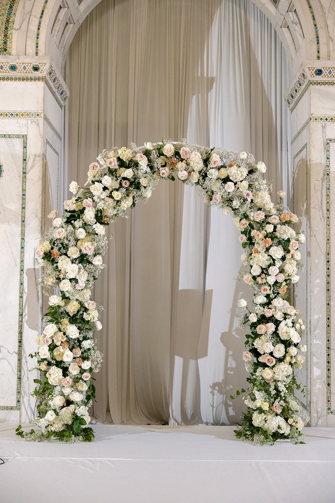 An elegant white floral arch in Preston Bradley Hall at Chicago Cultural Center, ready for the ceremony. Shot on film by a Chicago wedding photographer.
