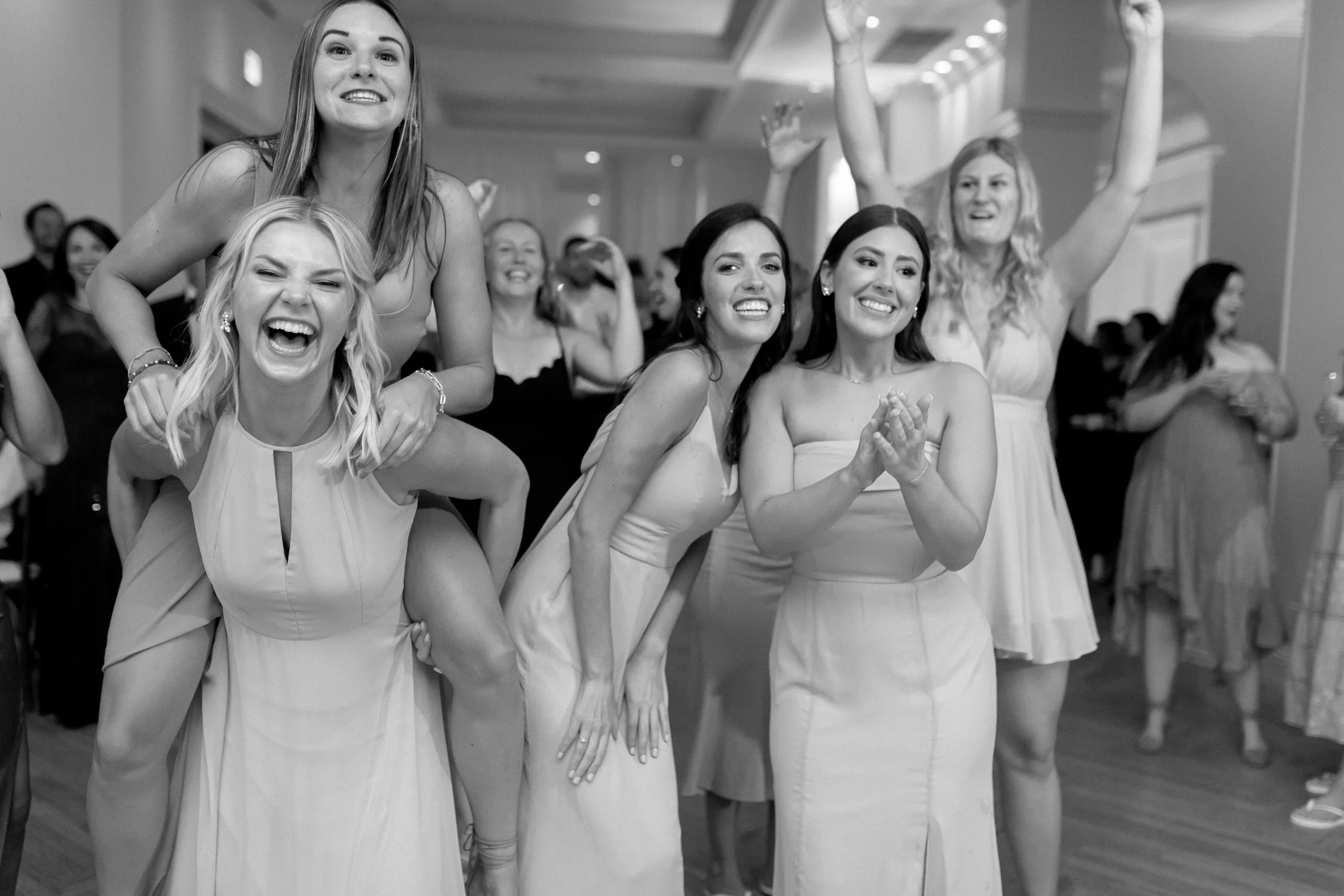 Bridesmaids laugh and celebrate on the reception dance floor at the Chicago Illuminating Company in this energetic black-and-white candid shot, pure joy all around.