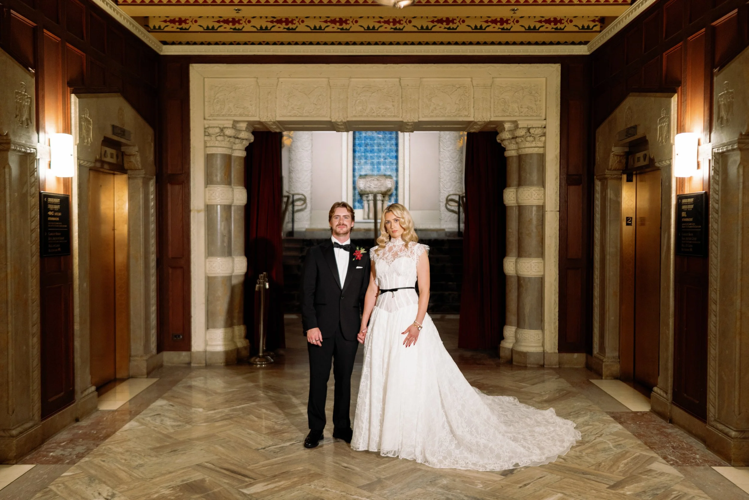 Bride and groom pose together in the vintage elevator lobby