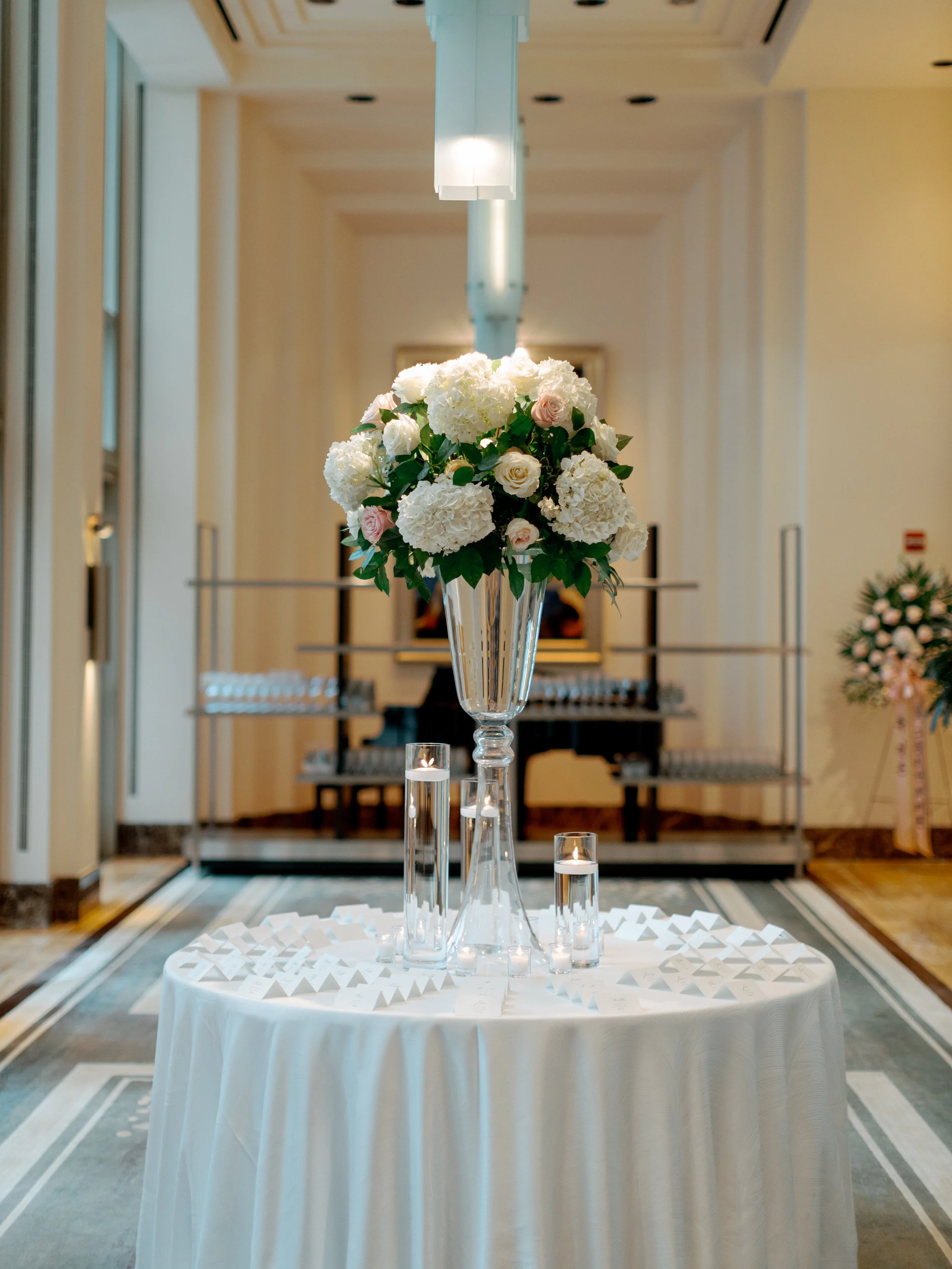 Tall silver urn arrangement of ivory roses and hydrangea welcoming guests in the Peninsula Chicago lobby for the wedding