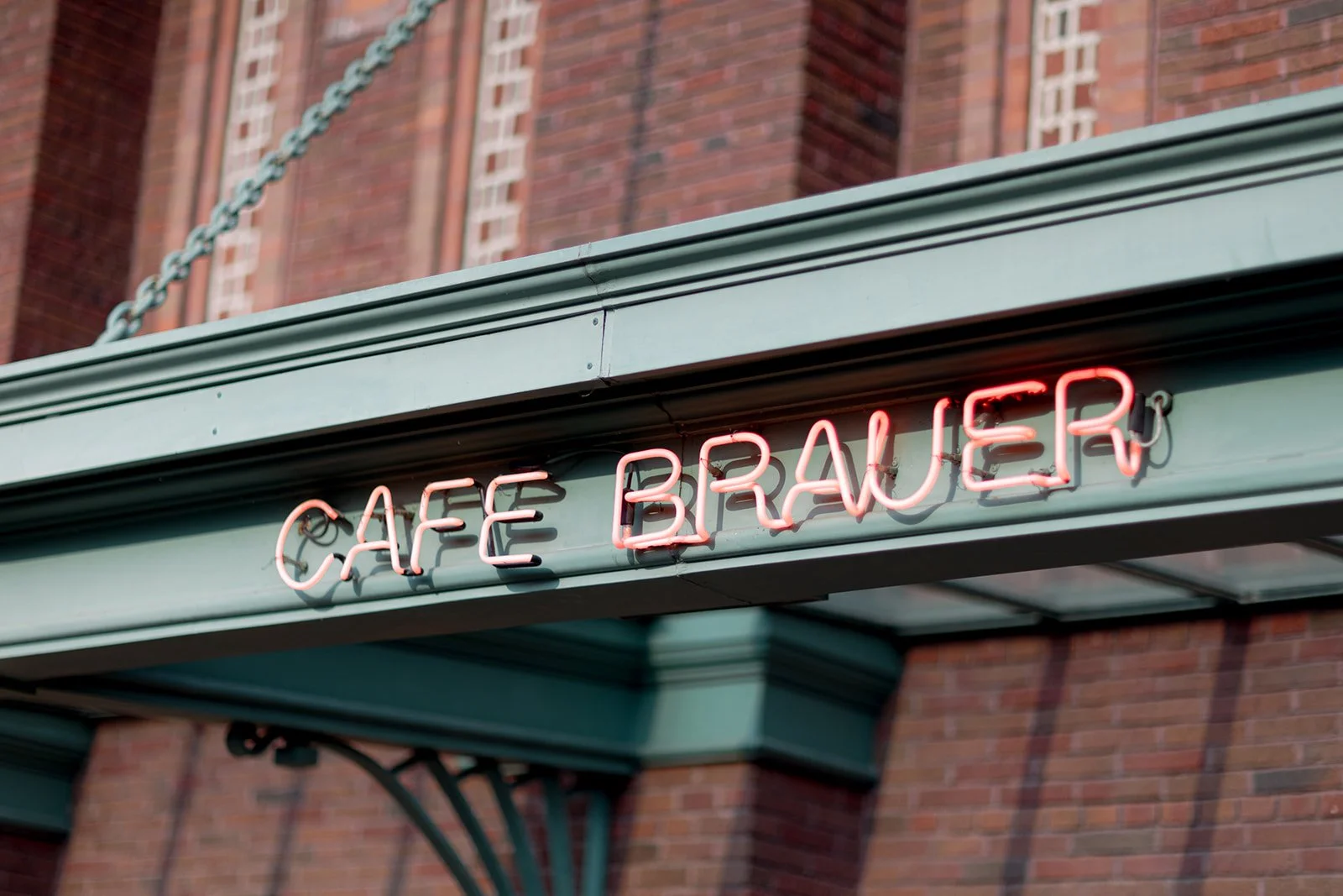 The Cafe Brauer neon sign glowing warm red above the venue's green-trimmed facade in Lincoln Park.