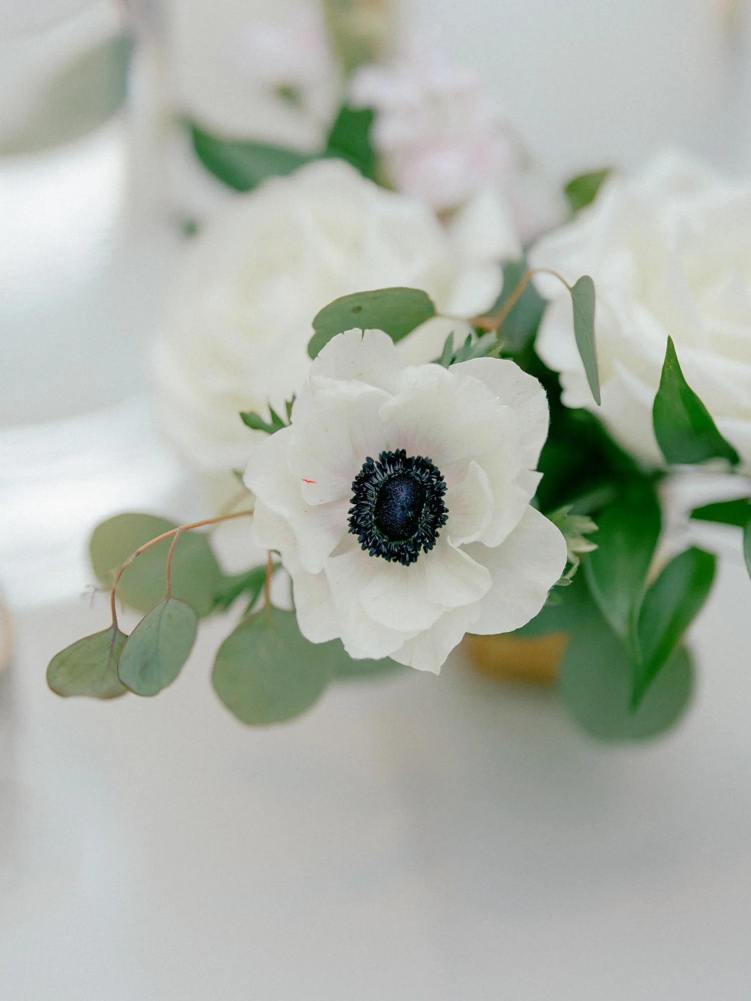 A delicate close-up of white anemone blooms and eucalyptus sprigs nestled beside the wedding cake at the Chicago Illuminating Company reception.