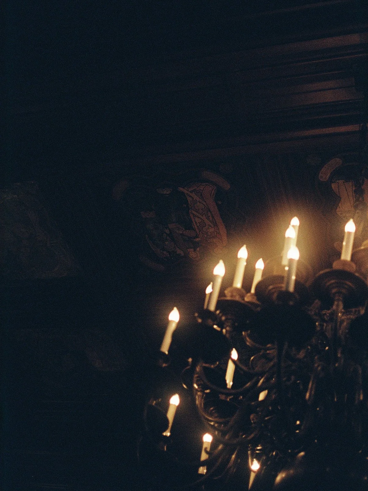 An ornate candelabra chandelier glows against the dark carved-wood ceiling of the University Club Chicago — moody, dramatic, and completely atmospheric. The kind of architectural detail that makes this venue impossible to replicate