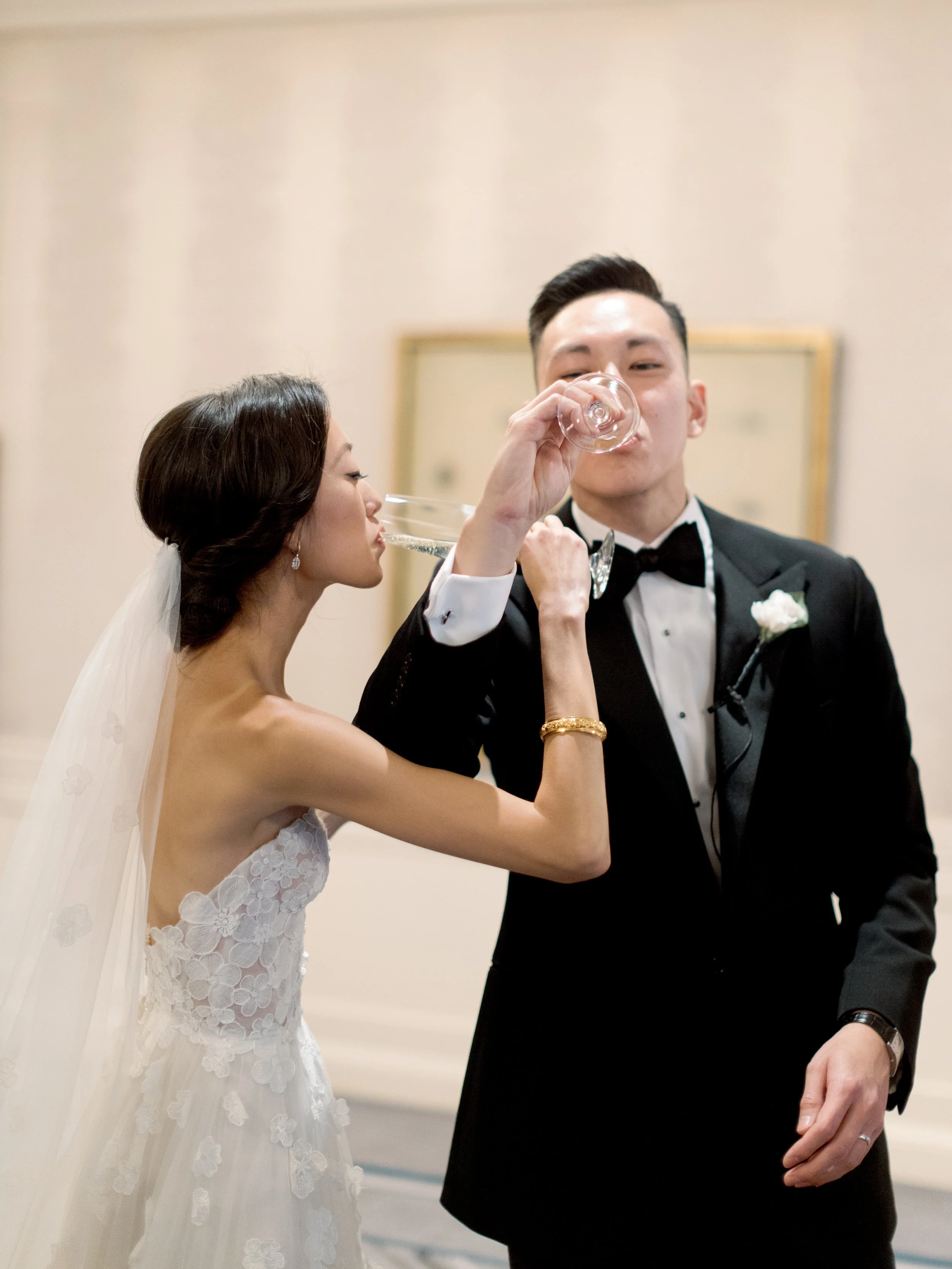 Film photograph of the bride lifting her champagne glass to the grooms lips for a playful sip at The Peninsula Chicago