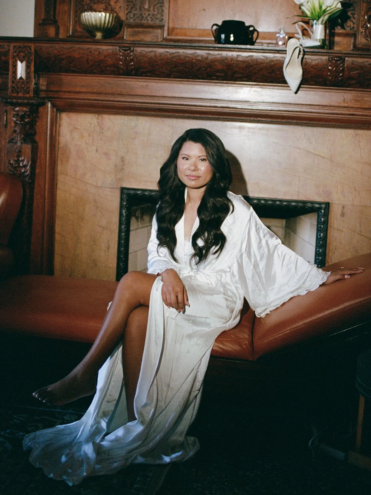 Sarah in a luxurious white robe, seated on leather furniture at the Chicago Athletic Association during getting ready. Shot on film by a Chicago film wedding photographer.
